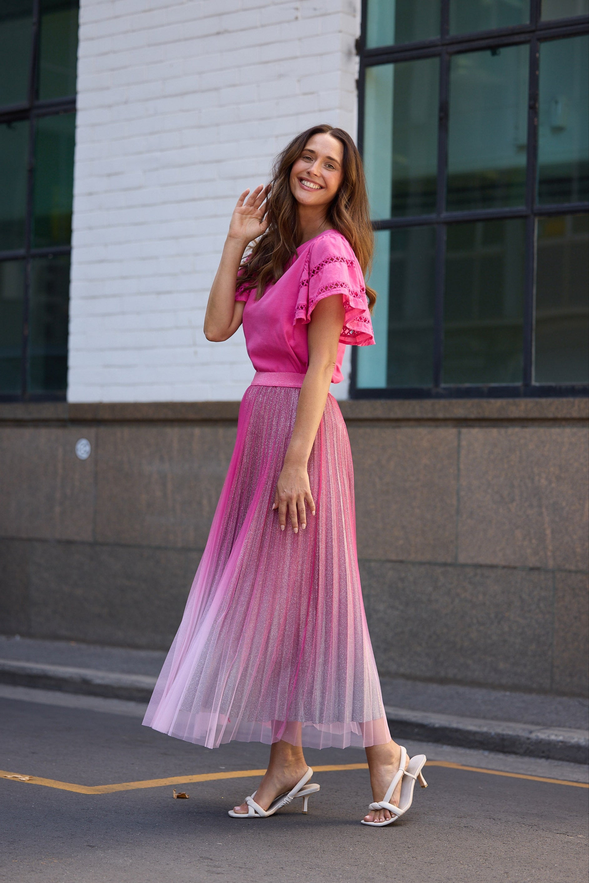 Woman in a pink outfit standing on a street with a building in the background