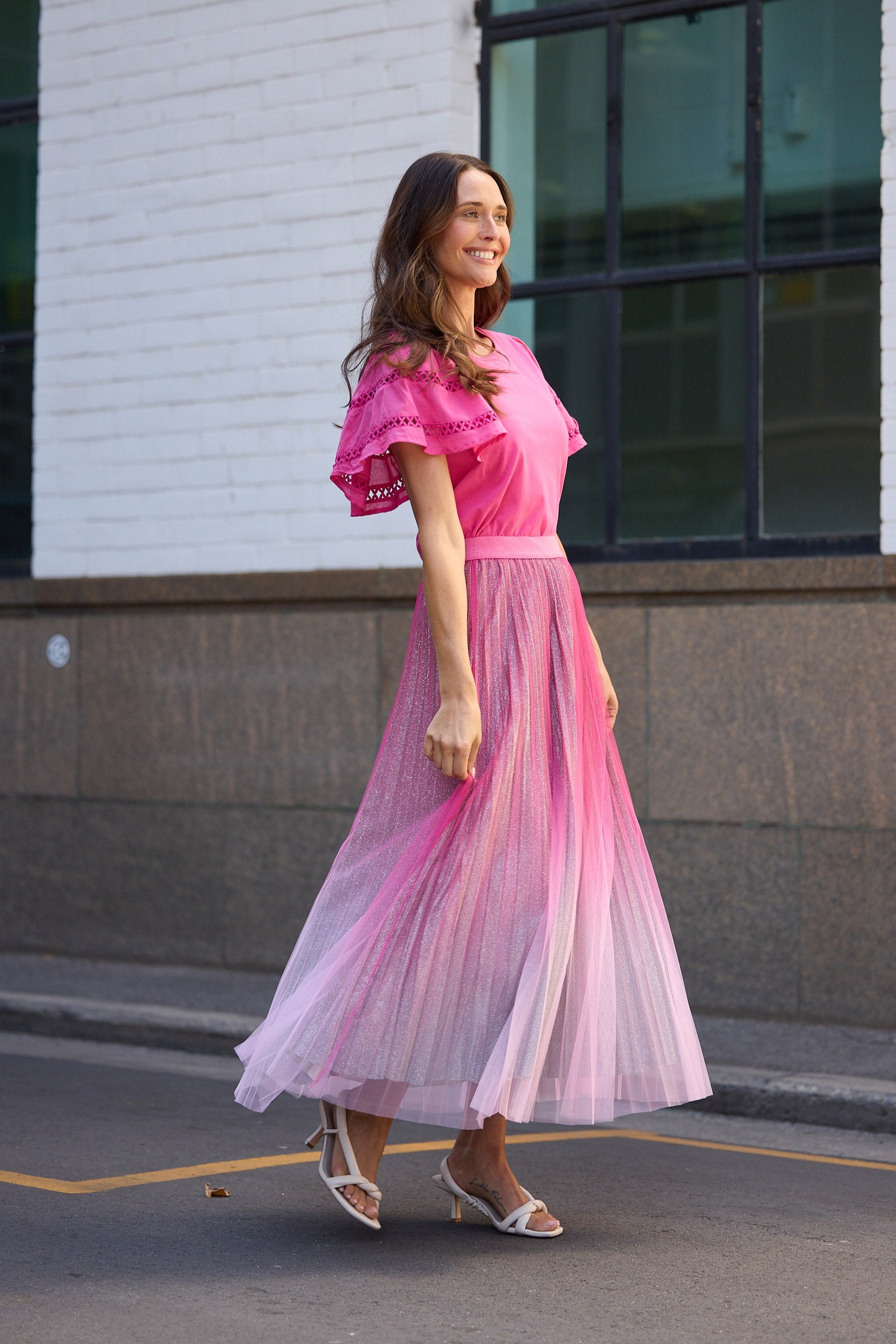 Woman in a pink dress standing on a street corner.