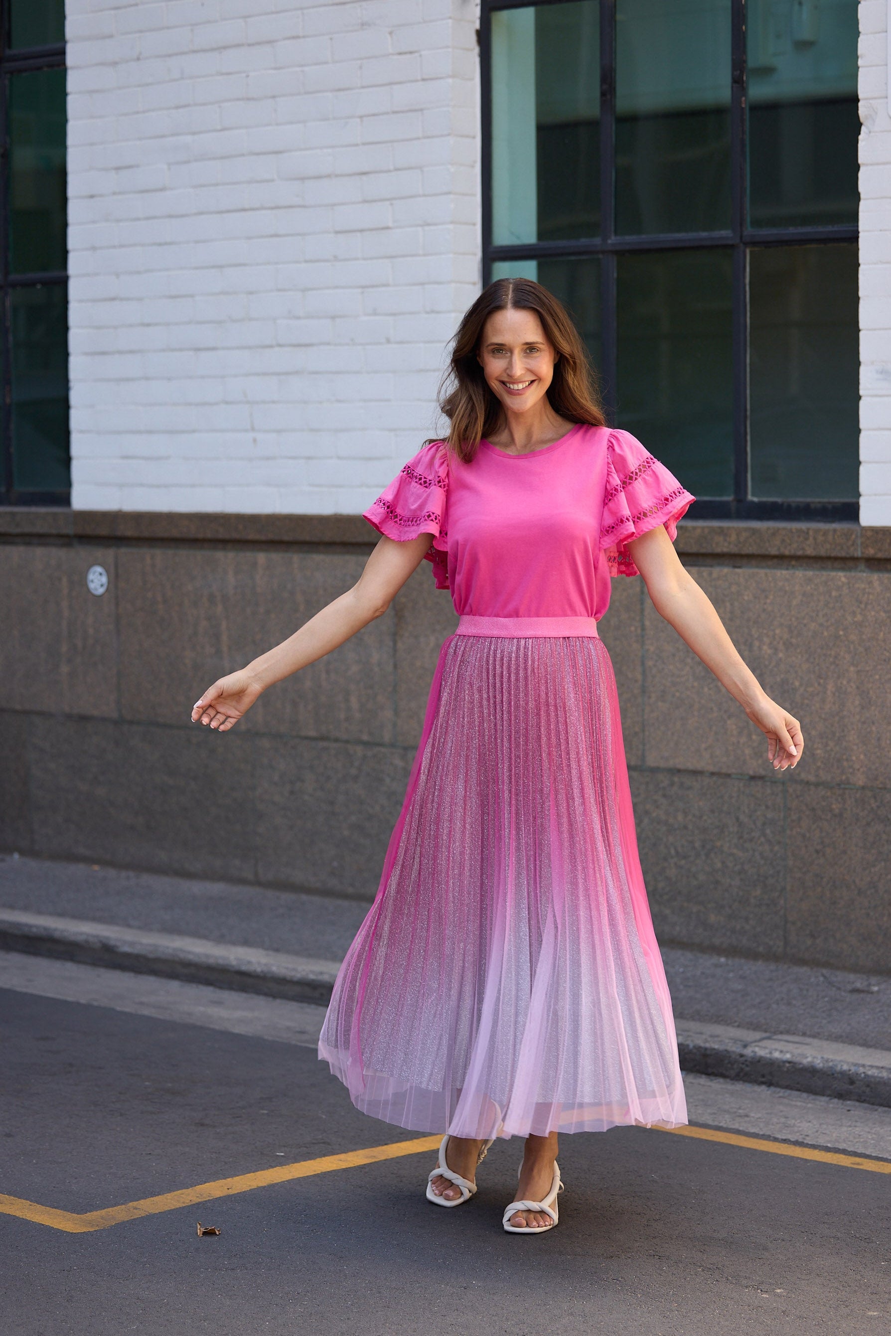 Woman in a pink dress standing on a street with a building in the background