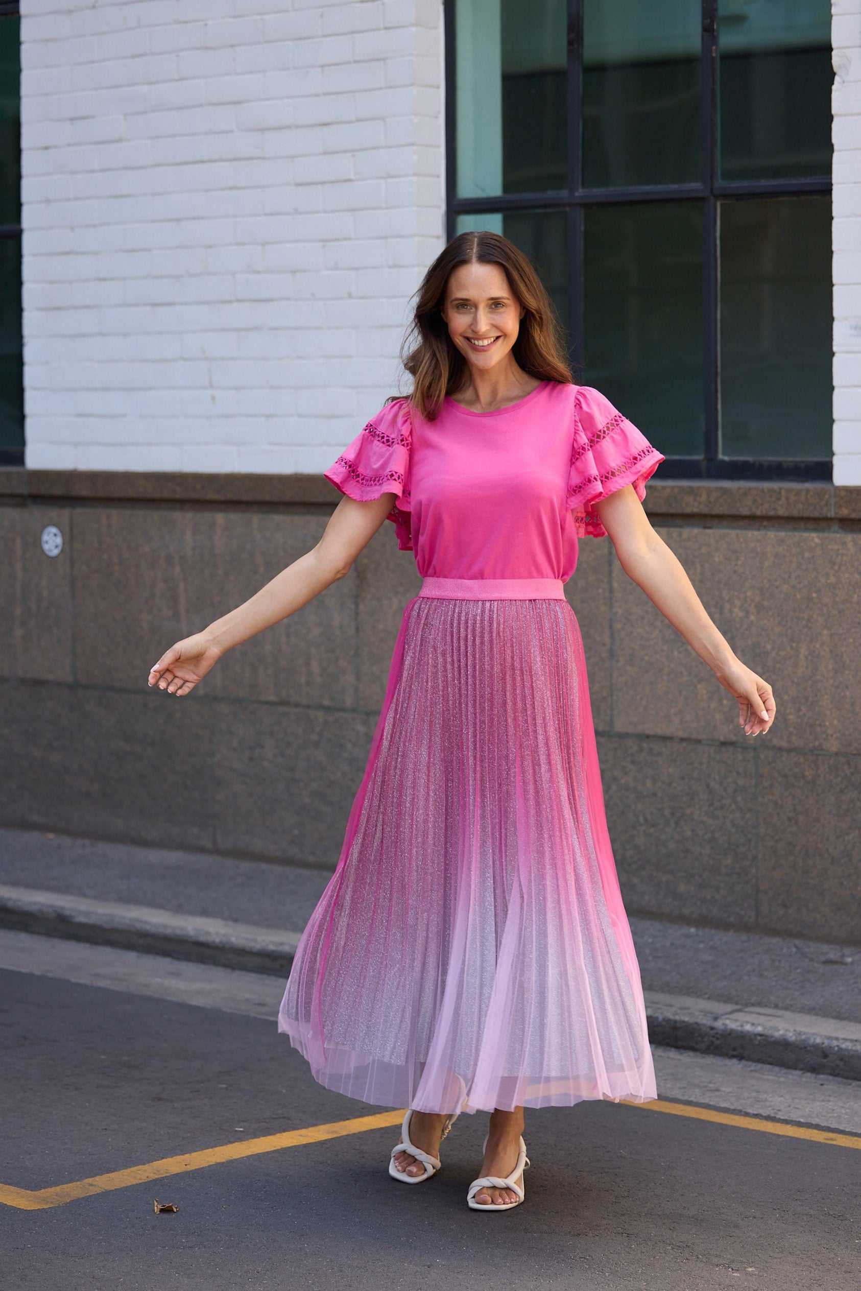 Woman in a pink dress standing on a street with a building in the background