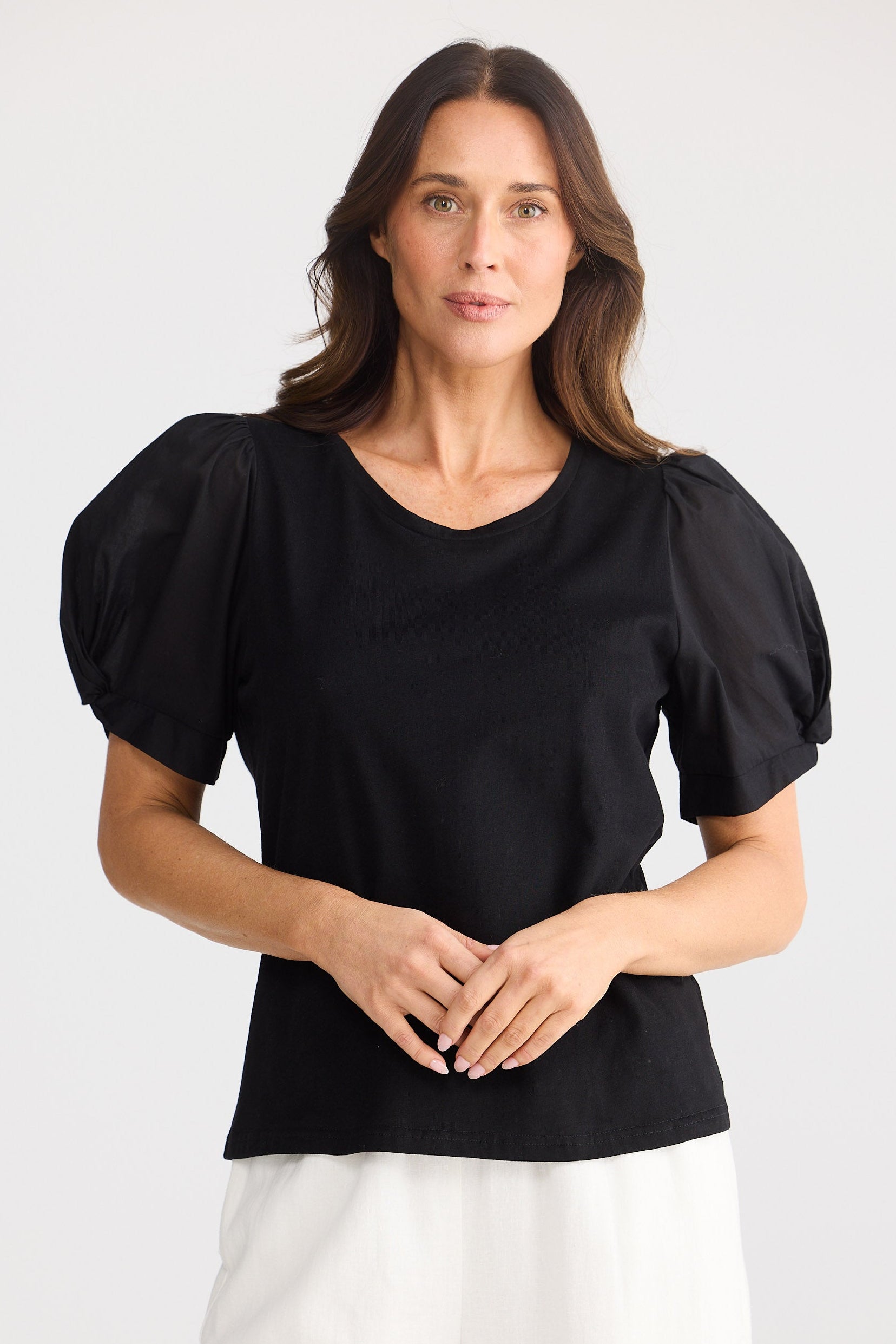 Woman wearing a black top with puff sleeves on a white background