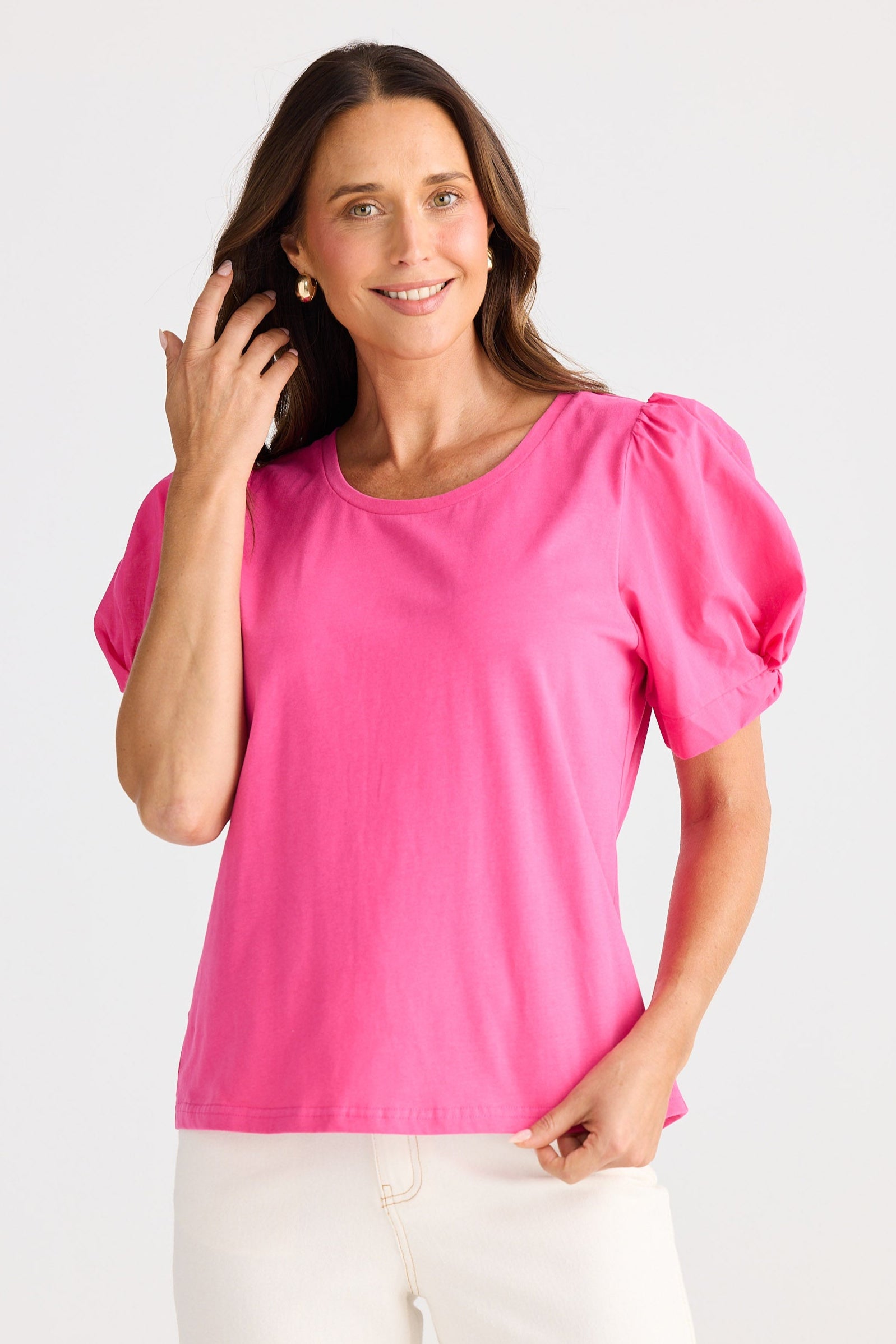 Woman wearing a bright pink top with puff sleeves on a white background