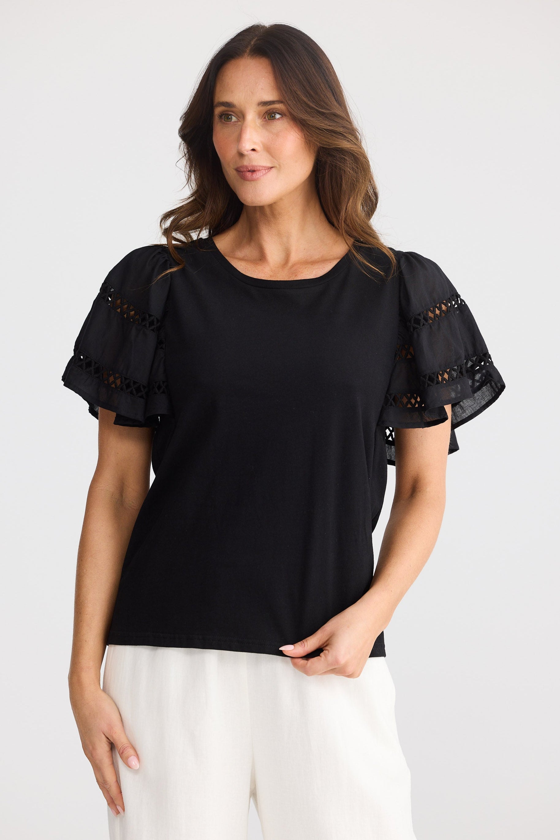 Woman wearing a black top with decorative sleeves on a white background