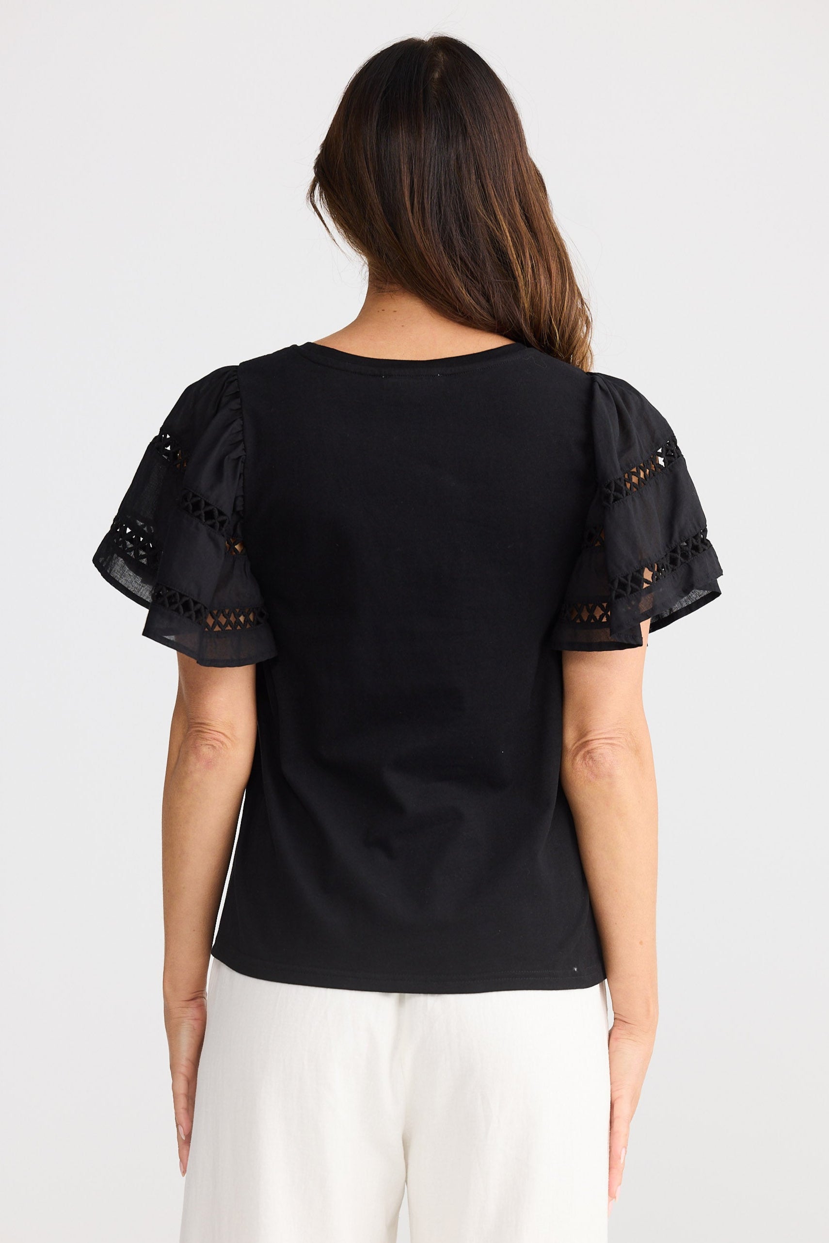 Woman wearing a black blouse with sheer sleeves on a white background