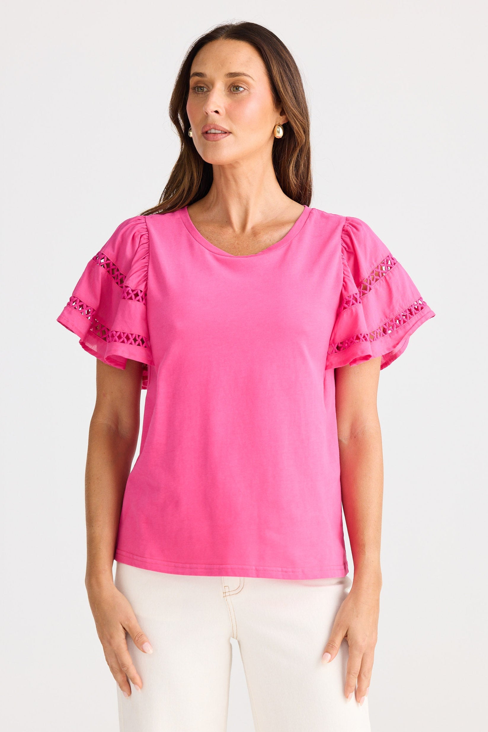 Woman wearing a pink blouse with lace sleeves on a white background