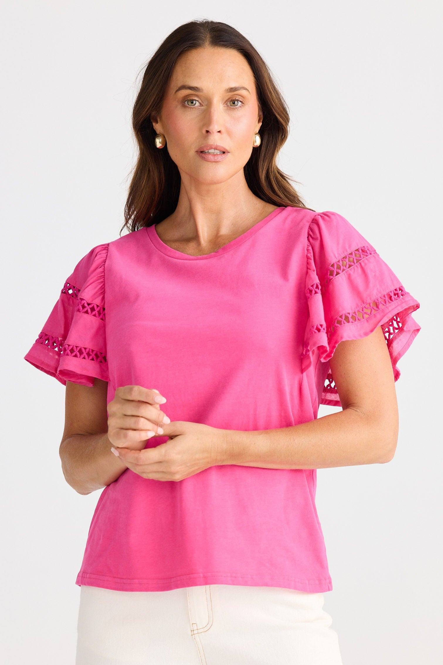 Woman wearing a pink blouse with ruffled sleeves on a white background