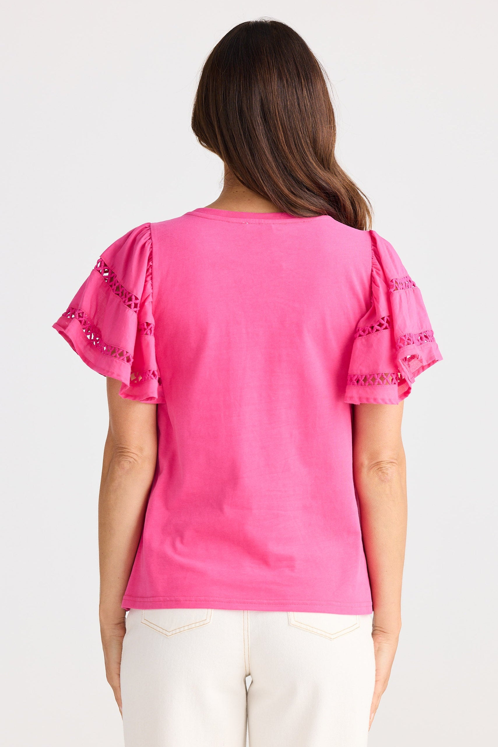 Woman wearing a pink blouse with decorative sleeves on a white background