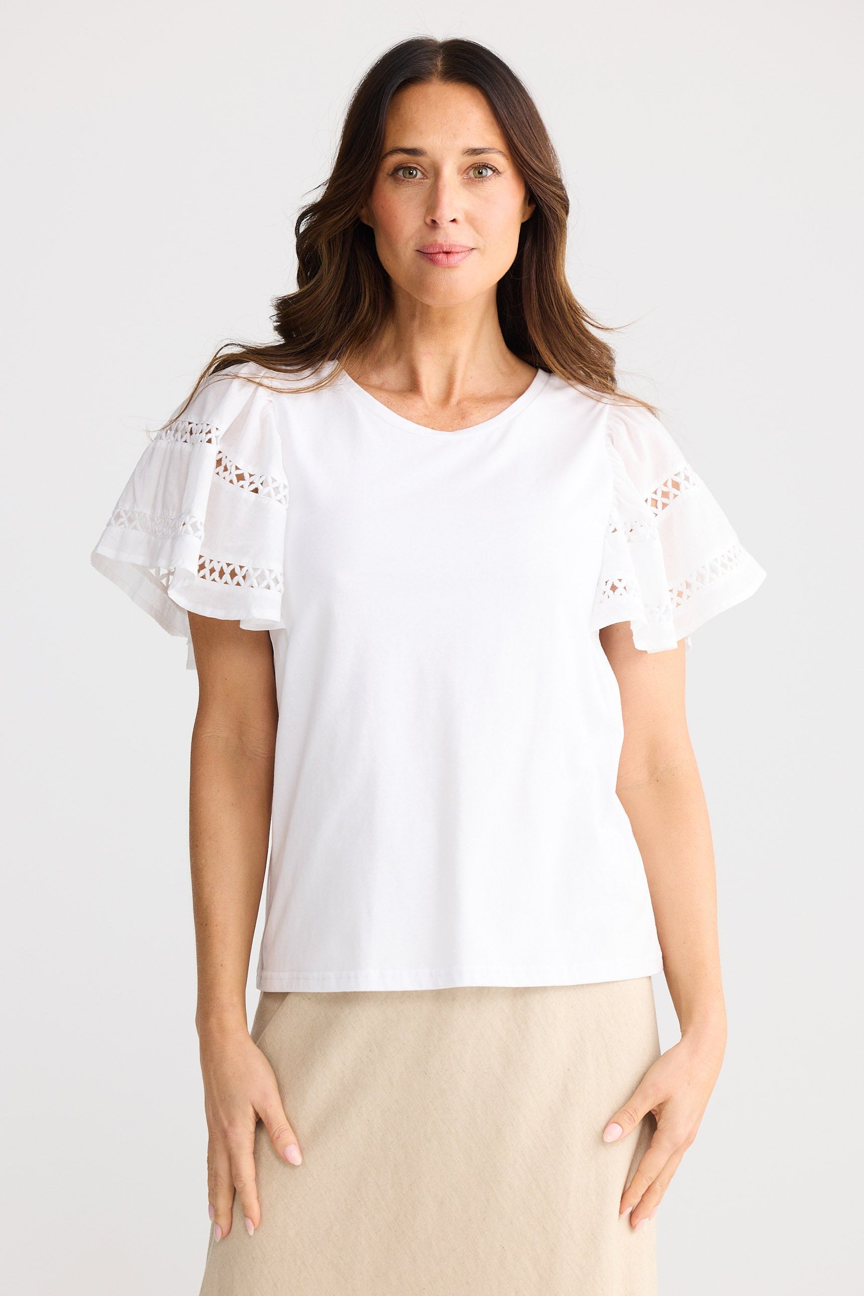 Woman wearing a white blouse with lace sleeves and trim on a white background