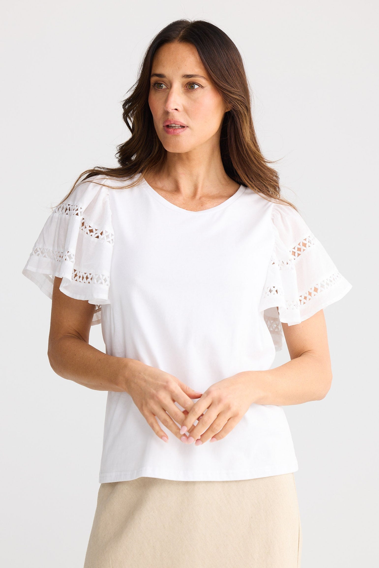 Woman wearing a white blouse with lace sleeves on a plain background