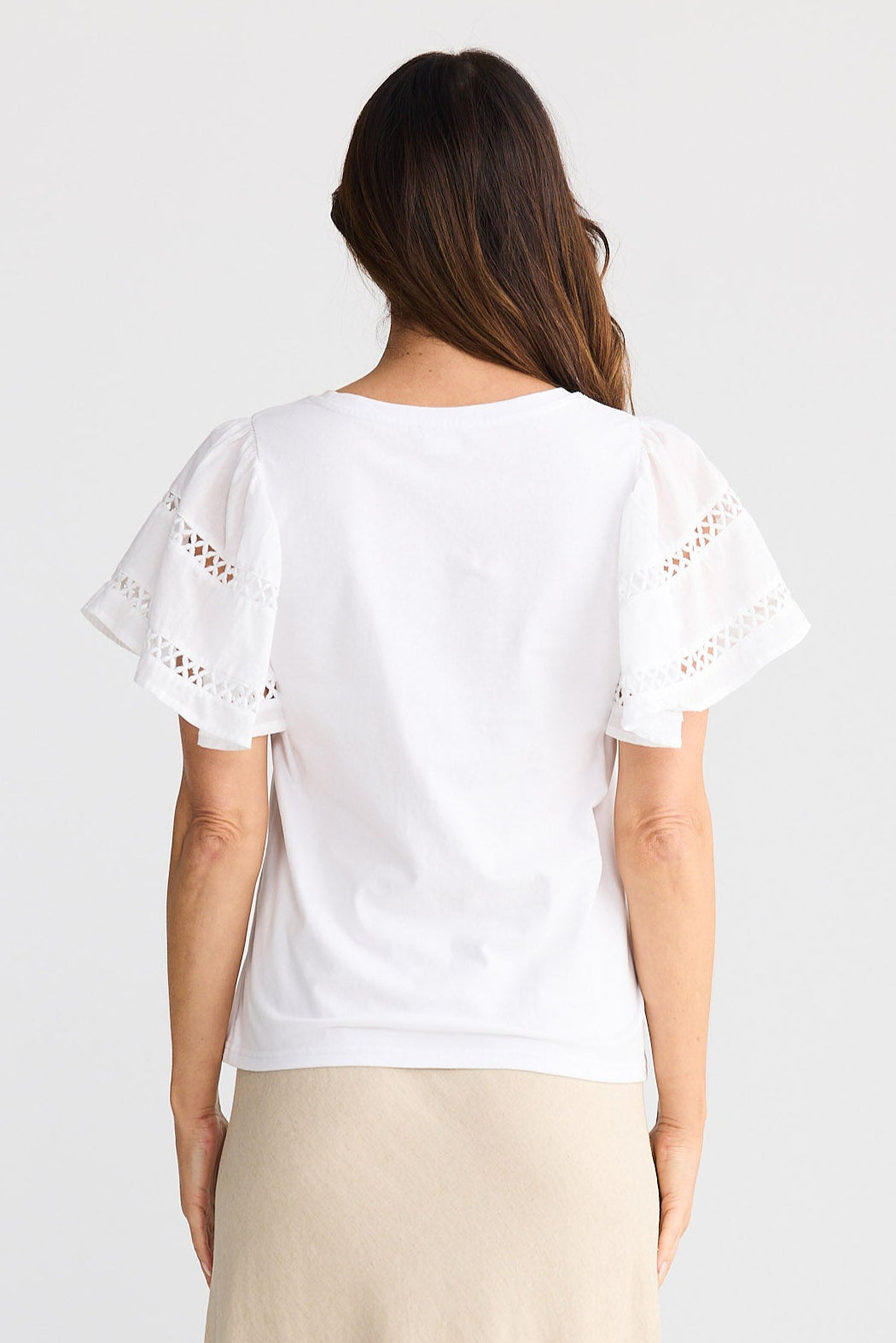 Woman wearing a white top and beige skirt on a white background