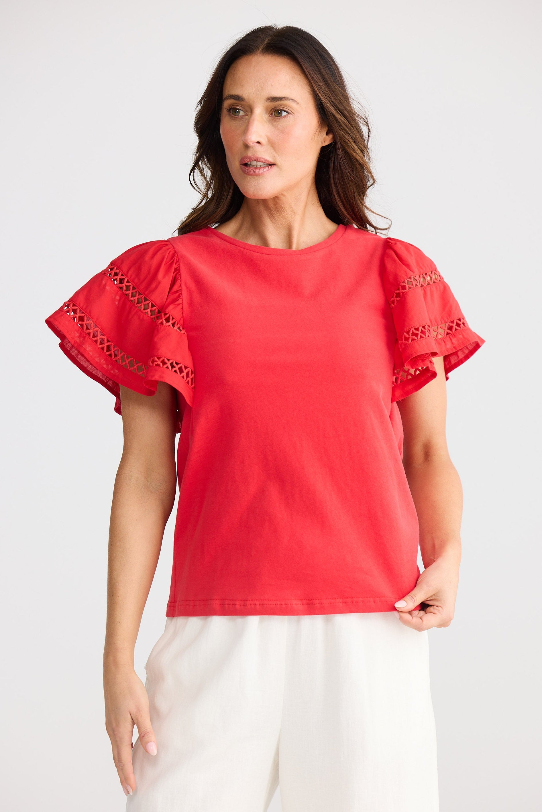 Woman wearing a red blouse with lace sleeves on a white background