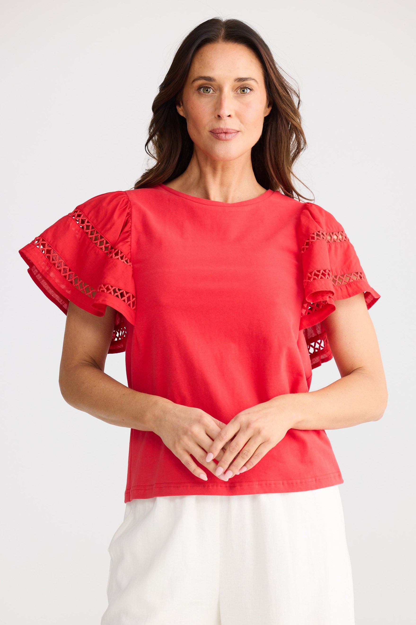 Woman wearing a red blouse with ruffled sleeves on a white background
