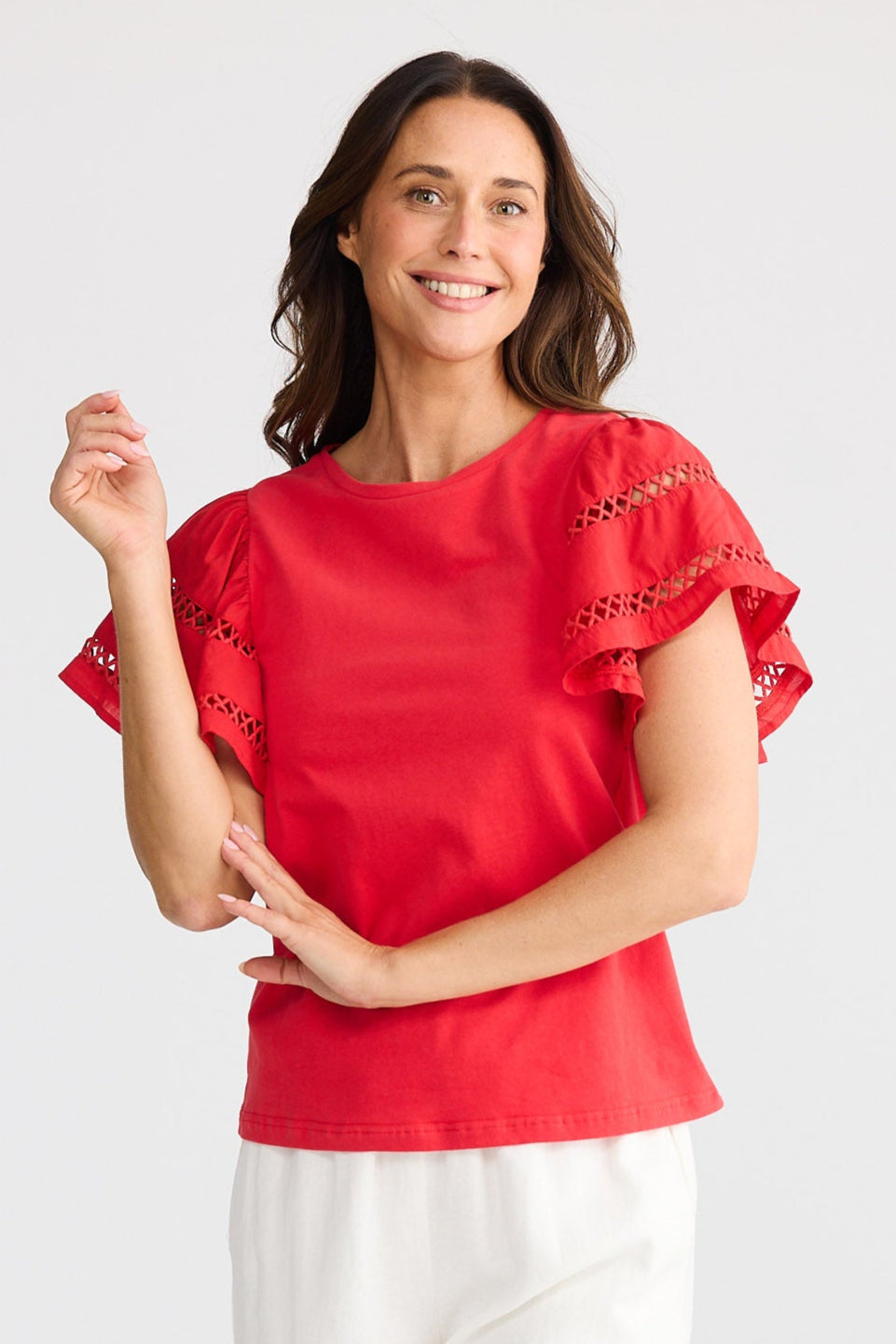 Woman wearing a red top and white pants on a white background