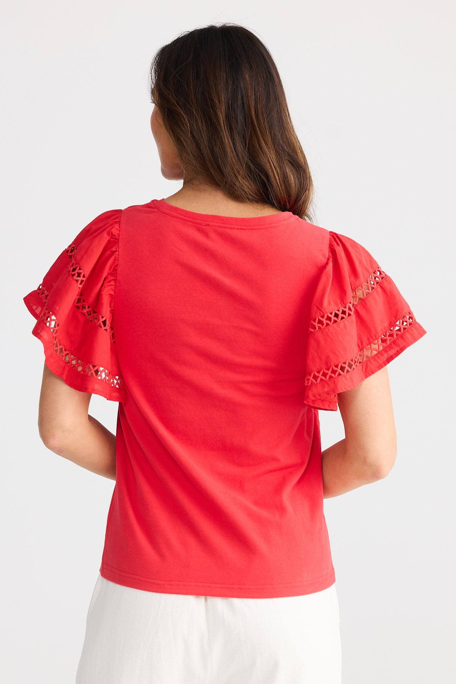 Woman wearing a red blouse with white pants on a white background