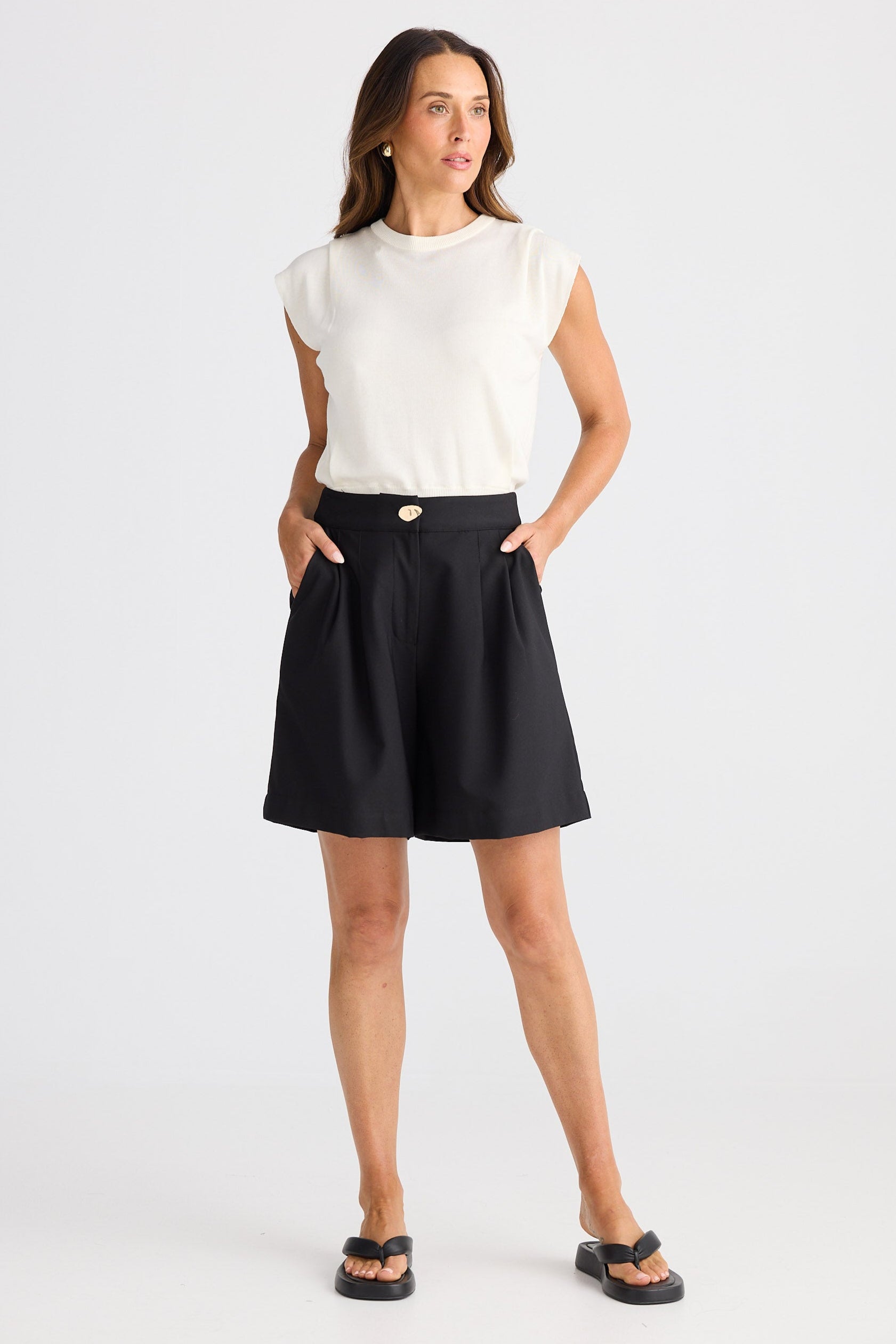 Woman wearing a white sleeveless top and black skirt on a white background
