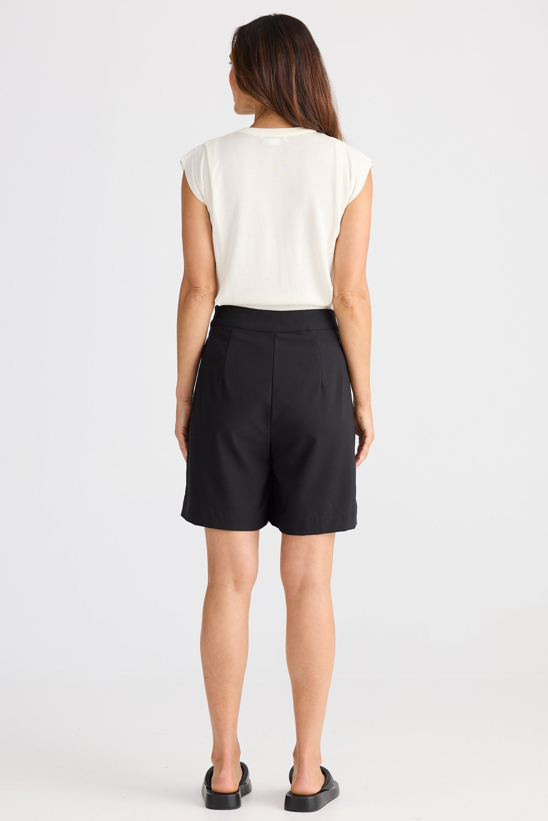 Woman wearing black shorts and a white top on a white background
