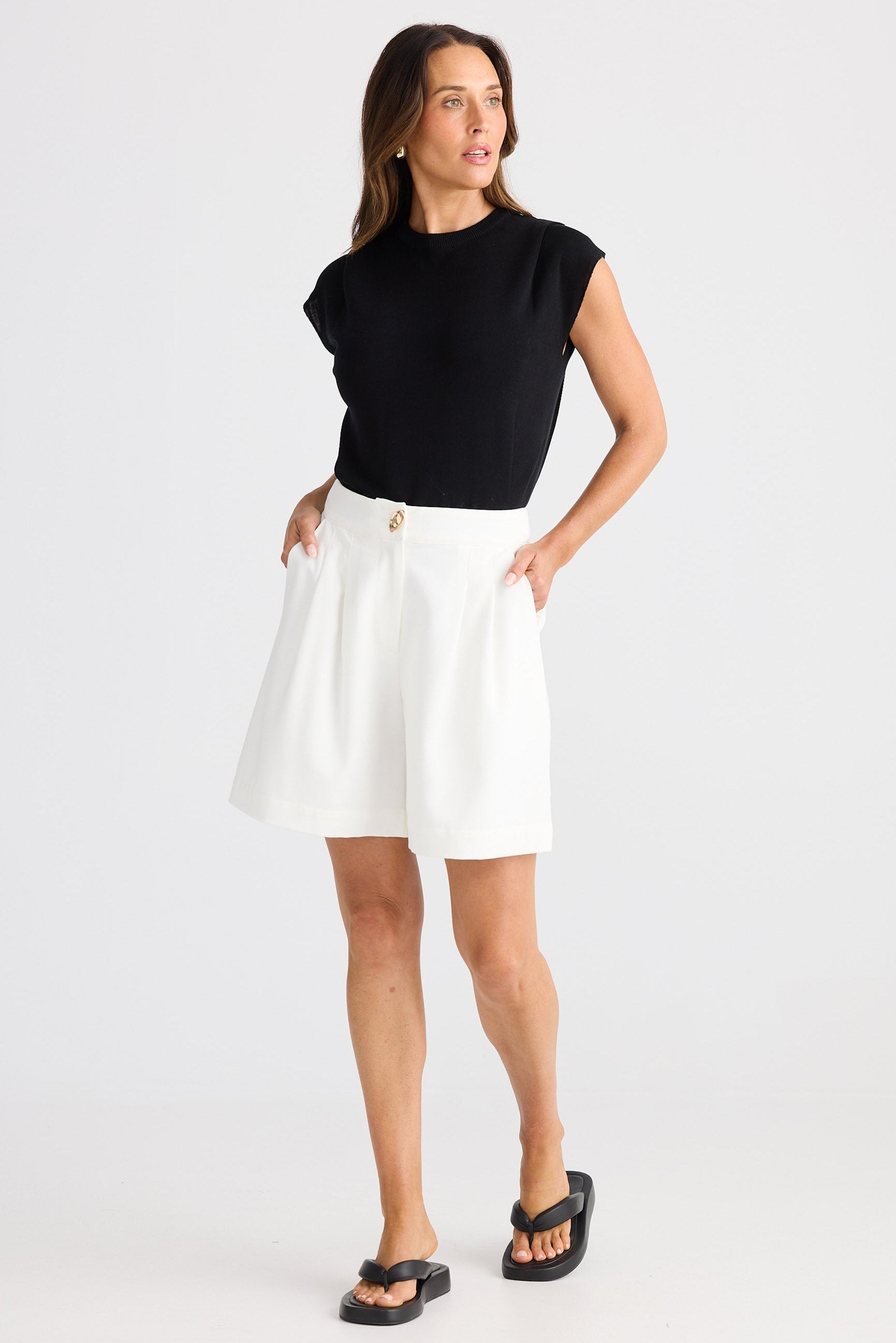 Woman wearing a black top and white skirt on a white background