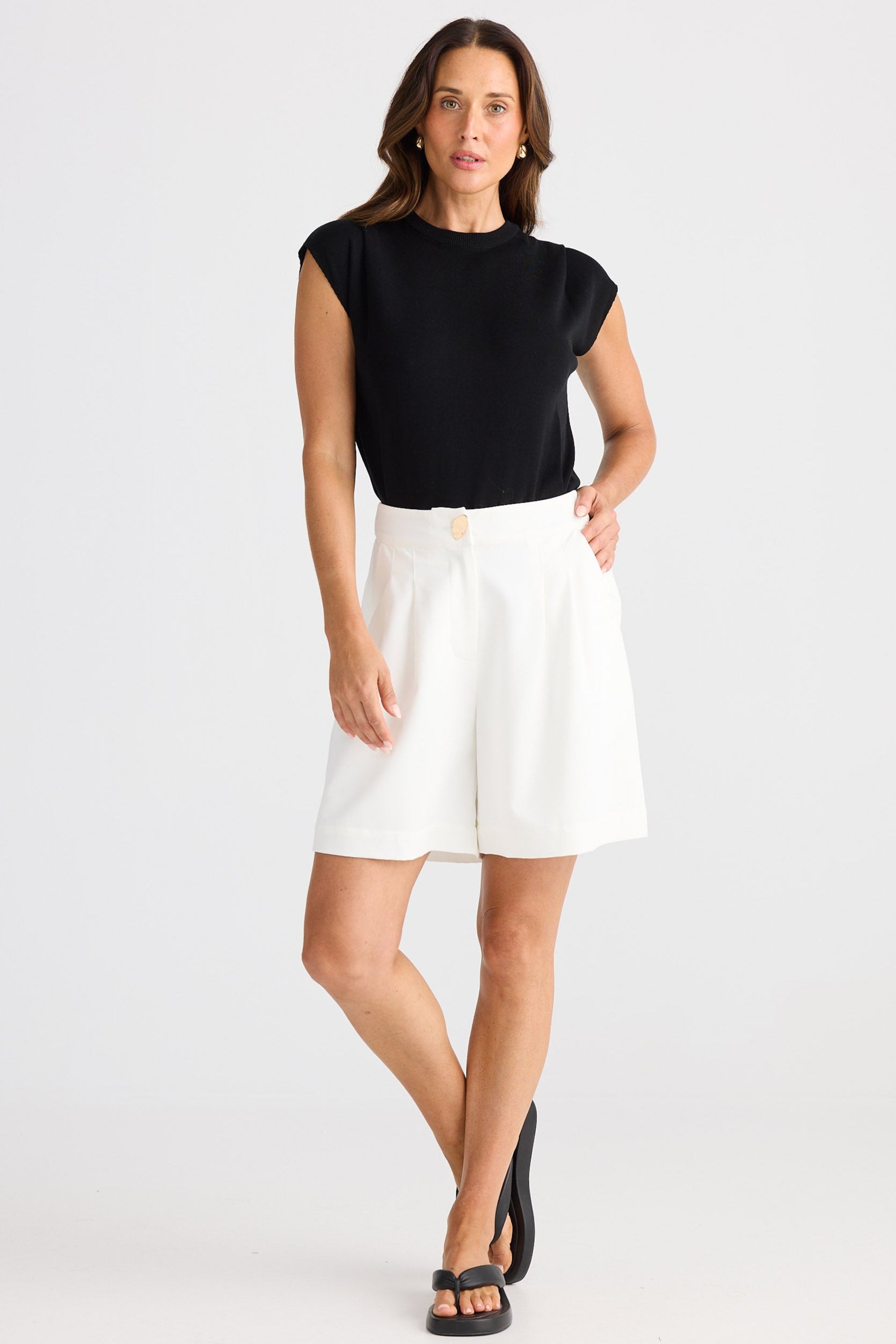 Woman wearing a black top and white shorts on a white background