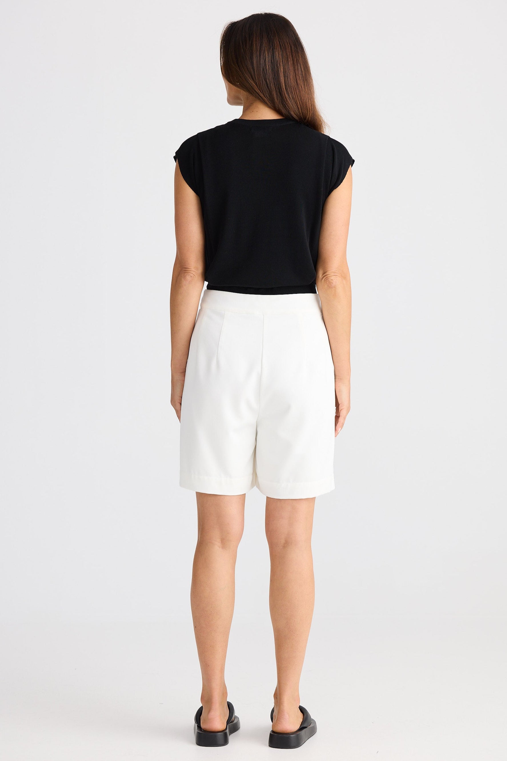 Woman wearing a black top and white shorts on a white background
