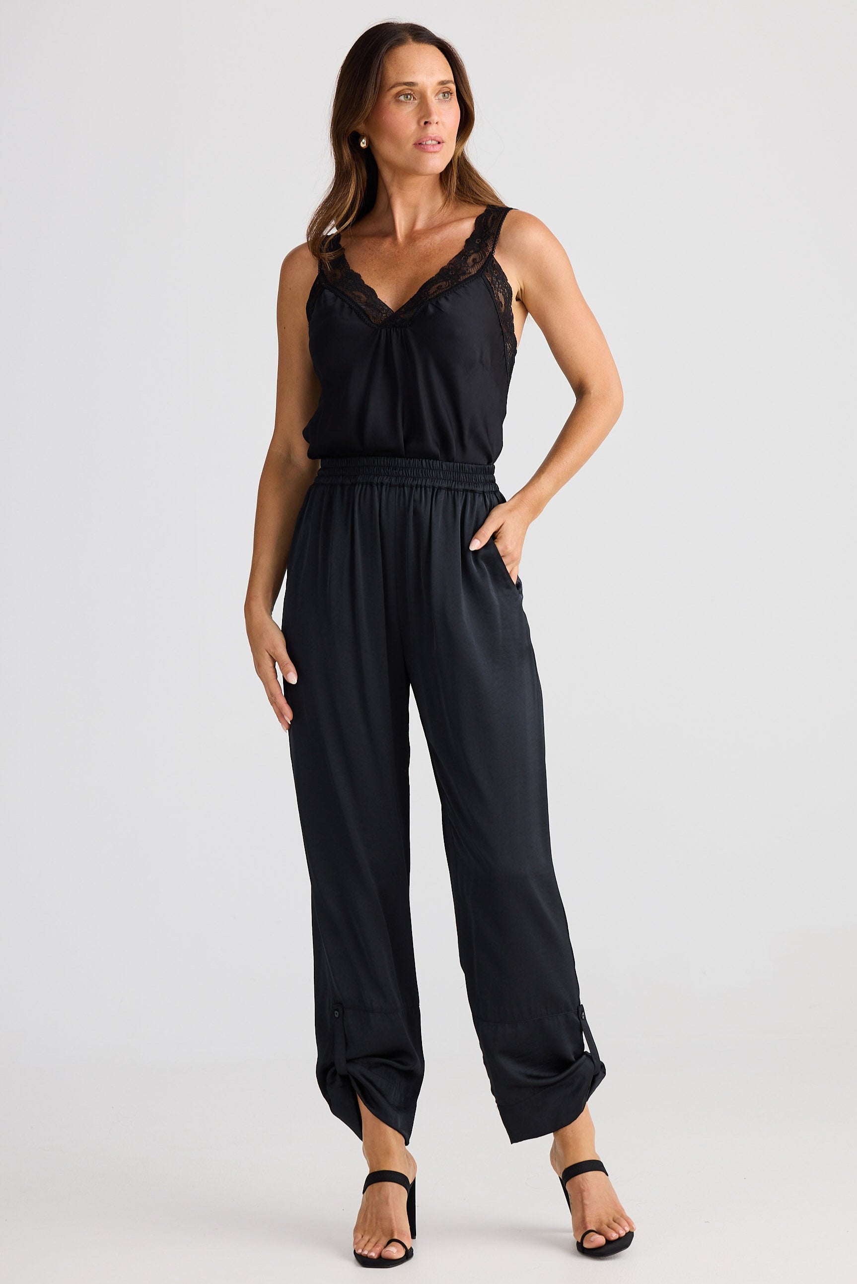 Woman wearing a black cami and pants on a white background