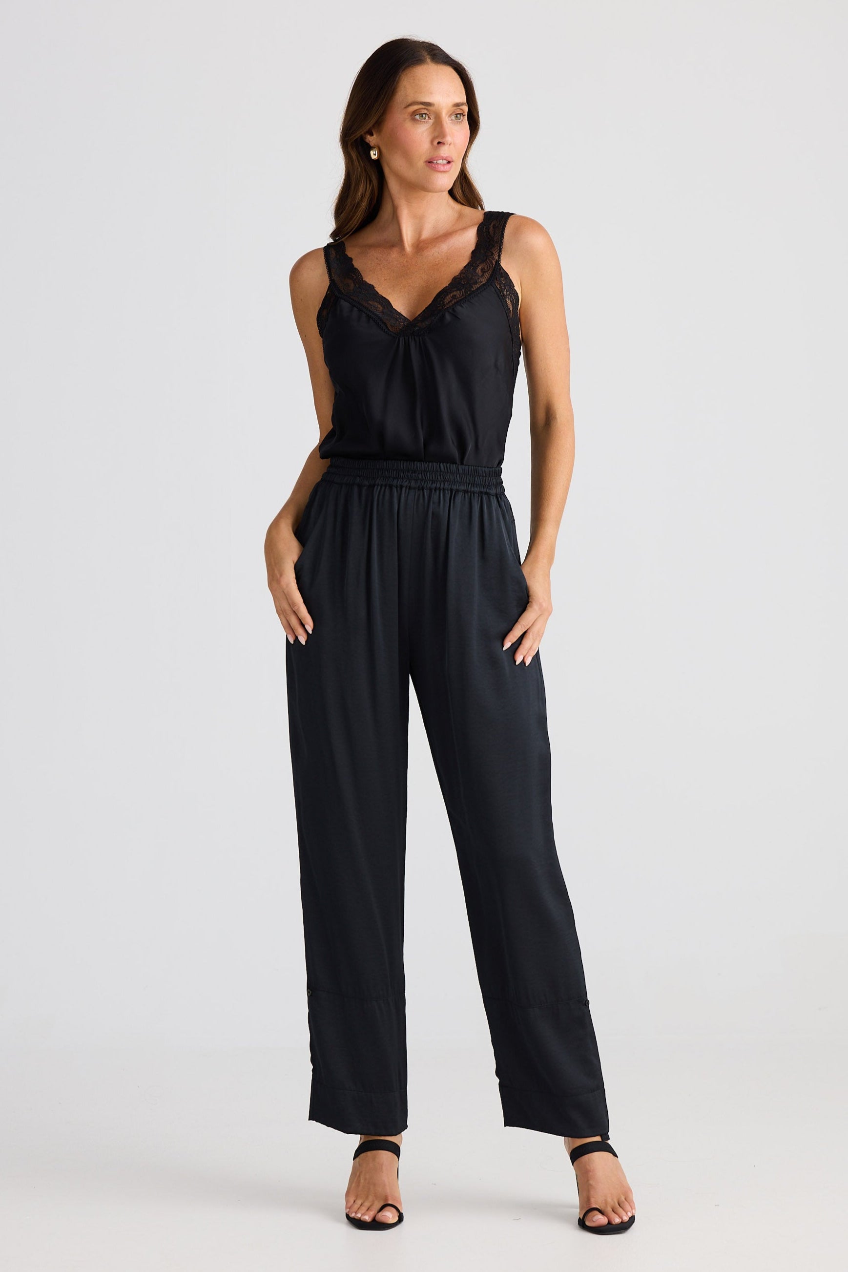 Woman wearing a black cami and pants on a white background