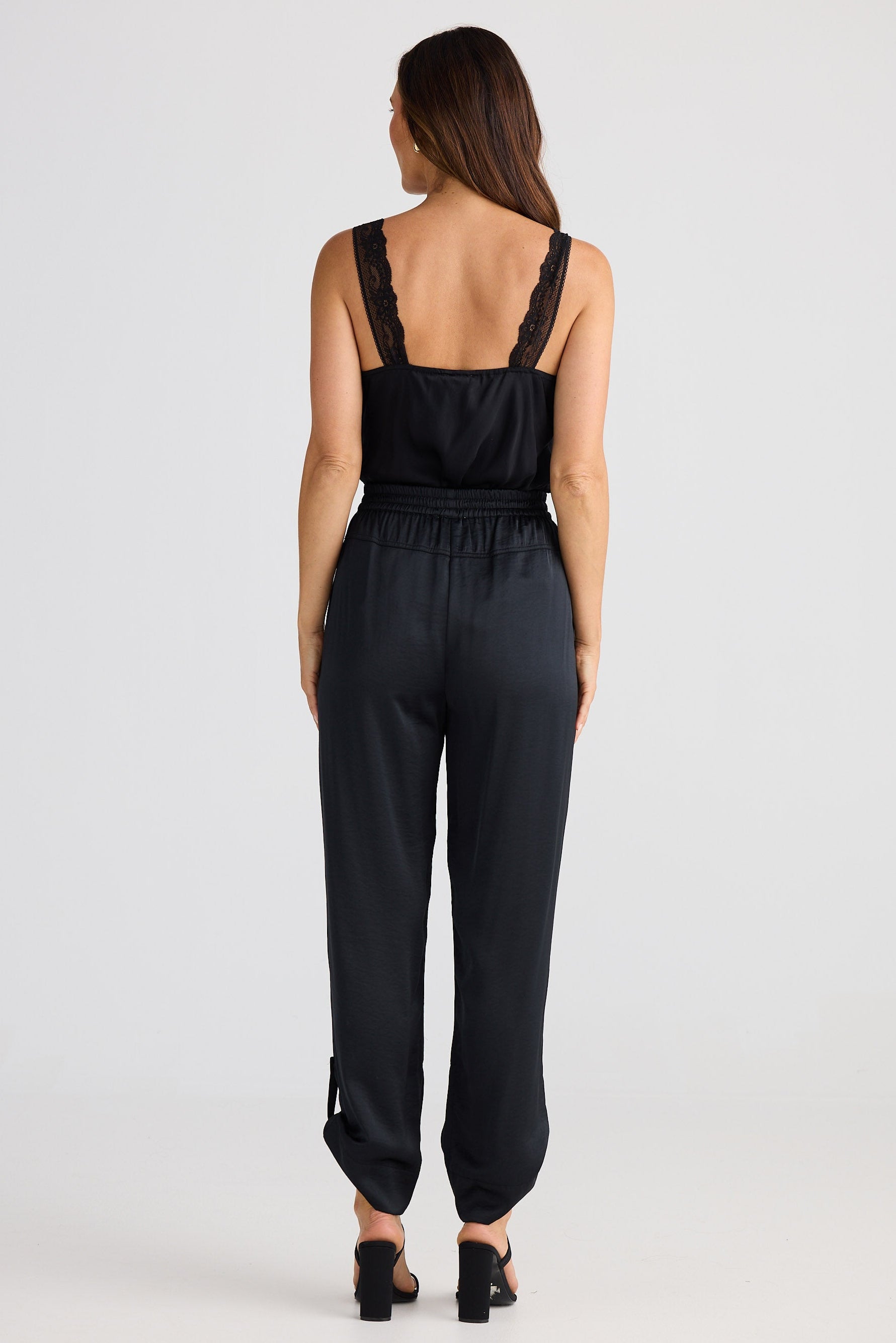 Woman wearing a black cami and pants on a white background