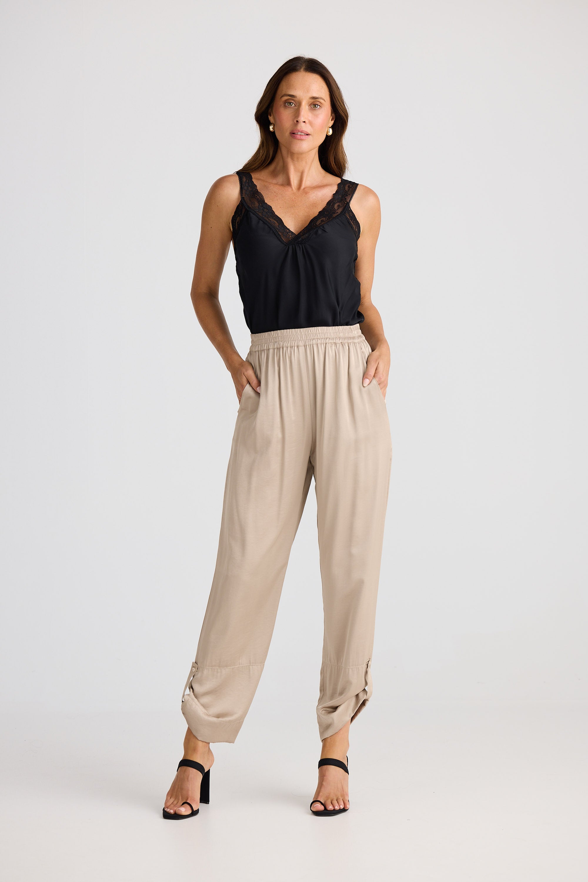 Woman wearing a black top and beige pants on a white background
