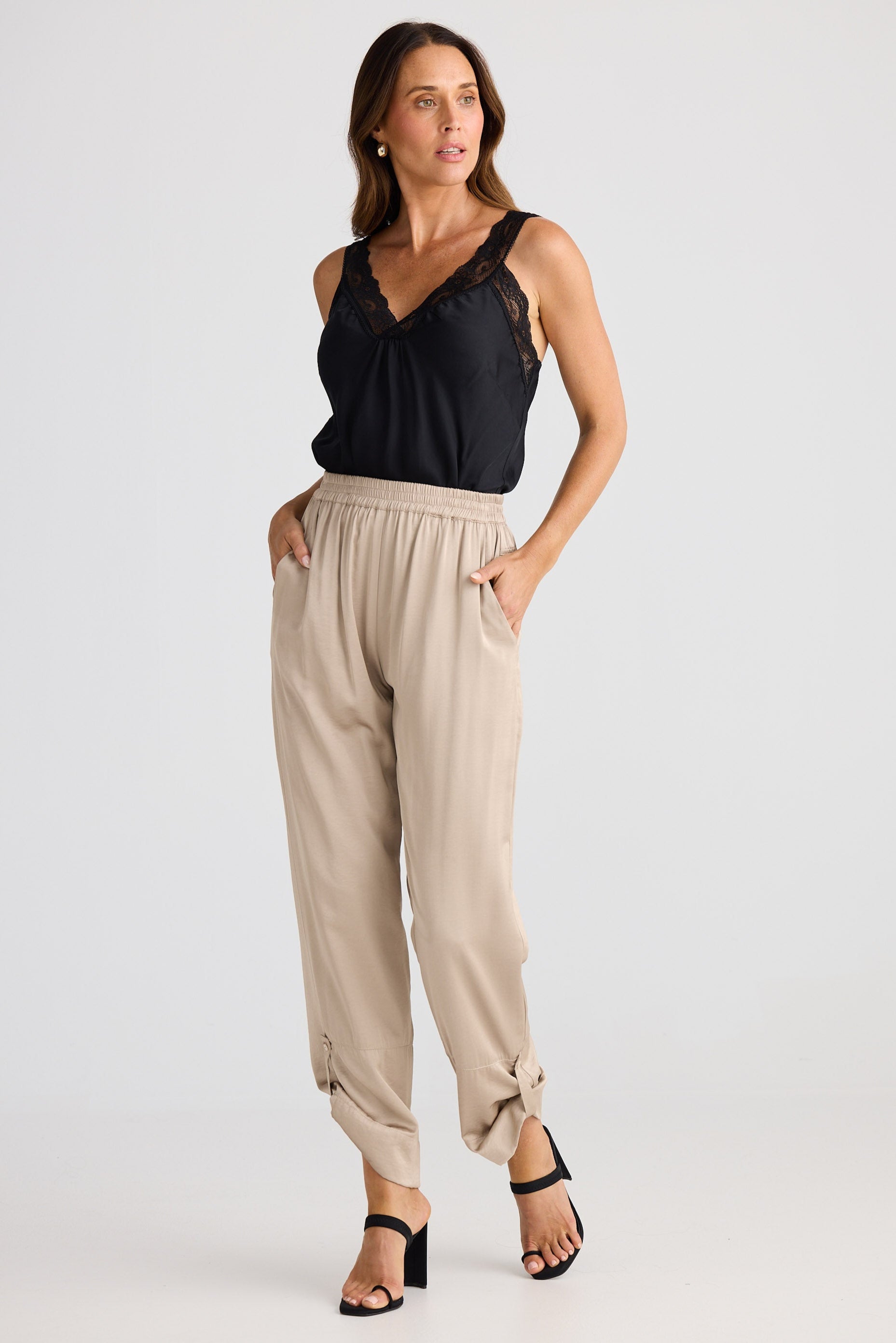 Woman wearing a black top and beige pants on a white background