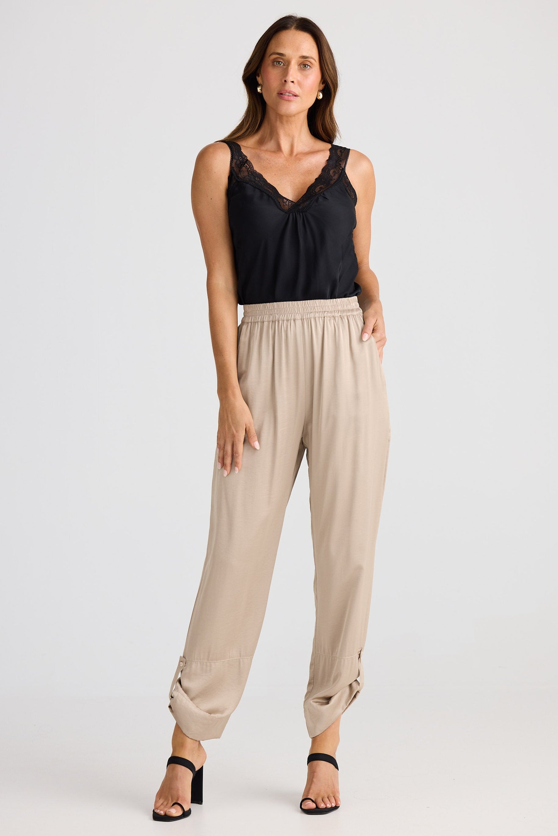 Woman wearing a black top and beige pants on a white background