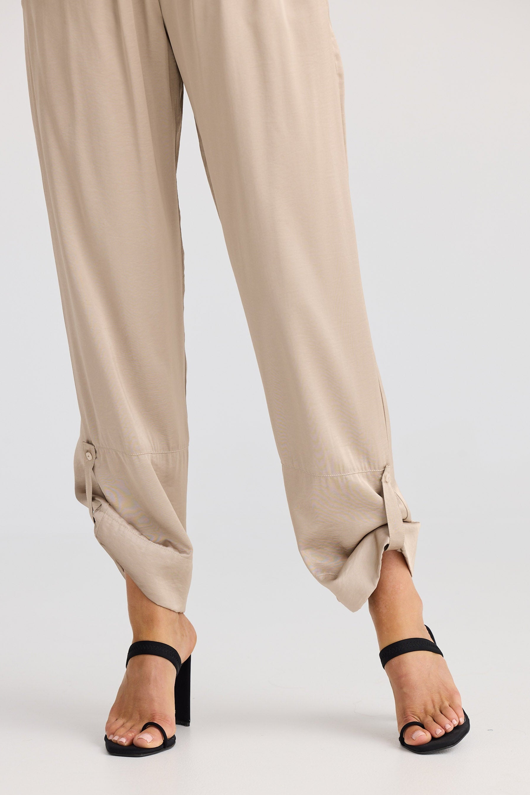 Beige pants worn by a person on a white background