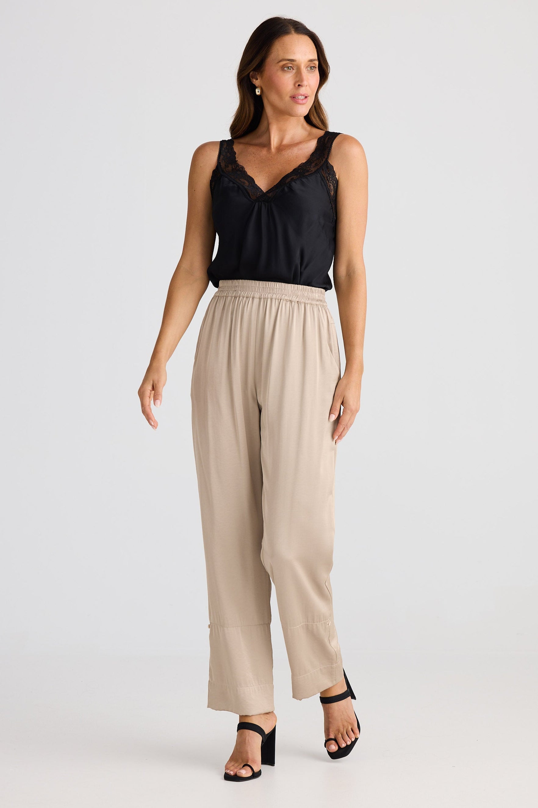 Woman wearing a black top and beige pants on a white background