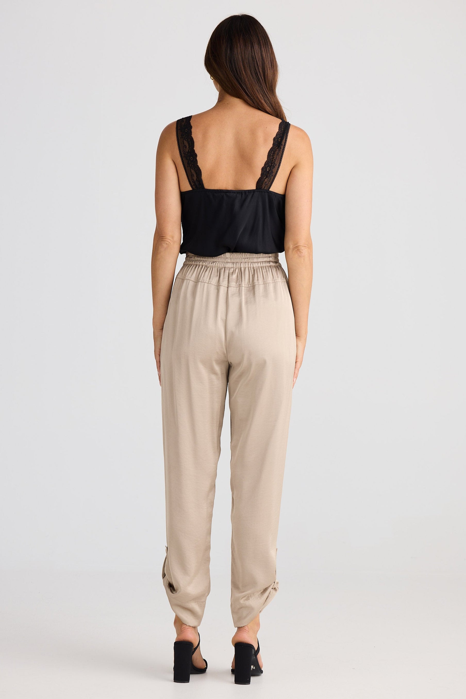 Woman wearing a black top and beige pants on a white background