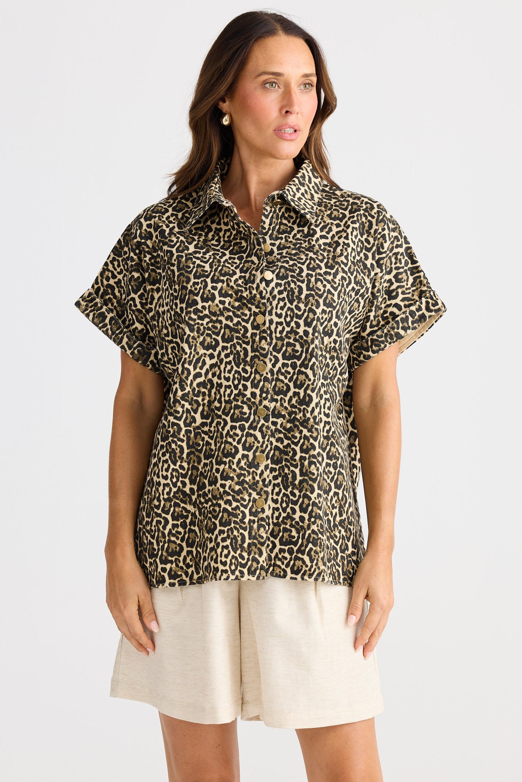 Woman wearing a leopard print shirt and white shorts on a light gray background