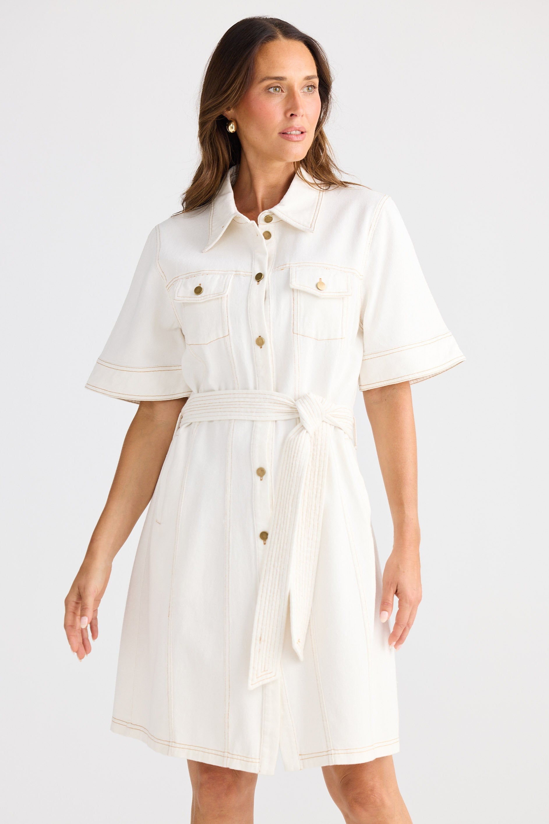 Woman wearing a white dress with gold buttons on a white background
