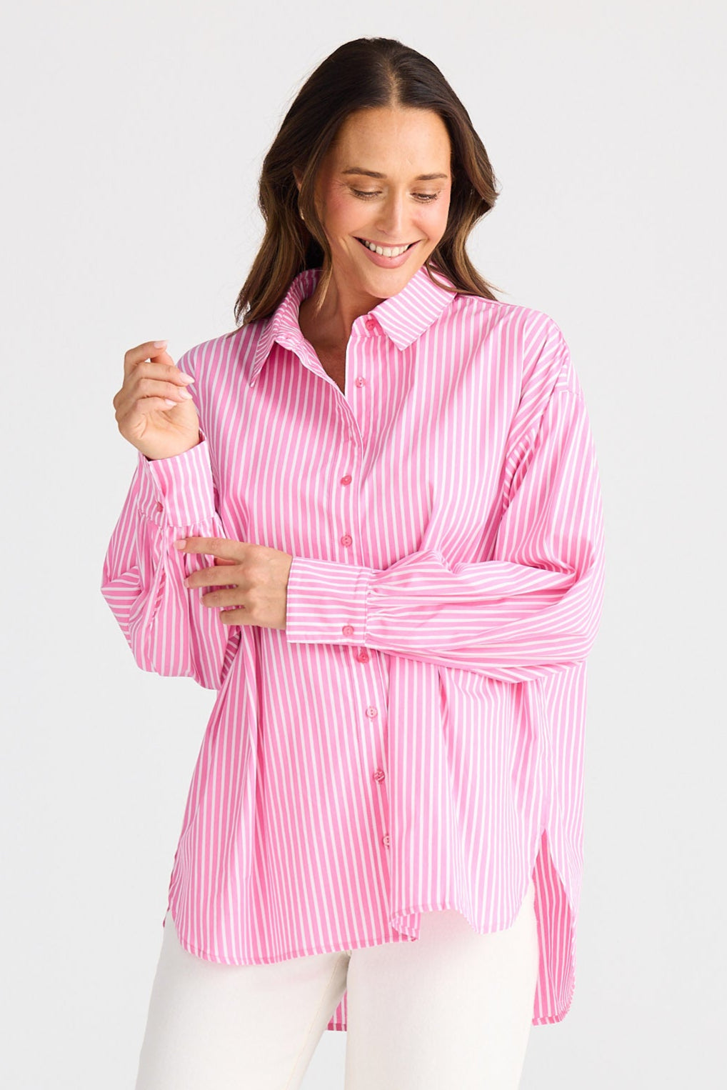 Woman wearing a pink striped shirt and white pants on a white background