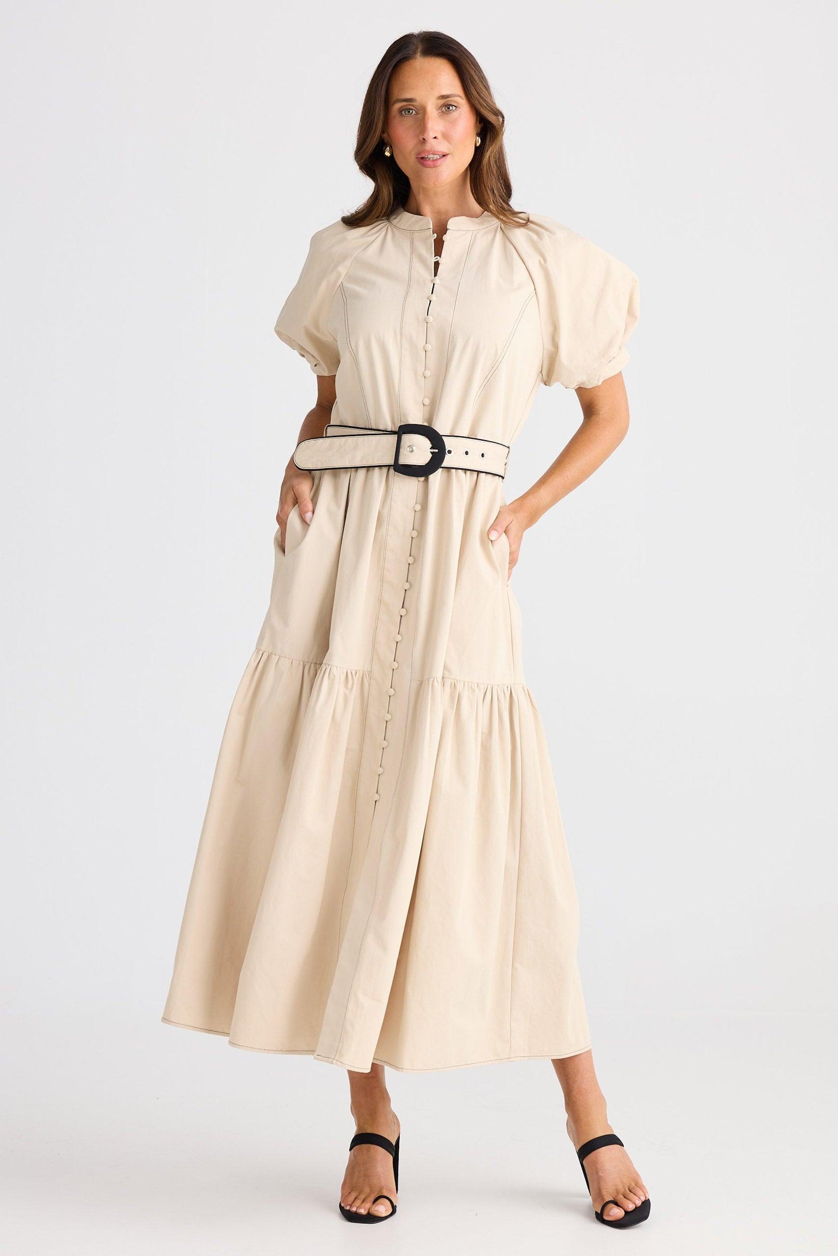 Woman wearing a beige dress with puff sleeves on a white background