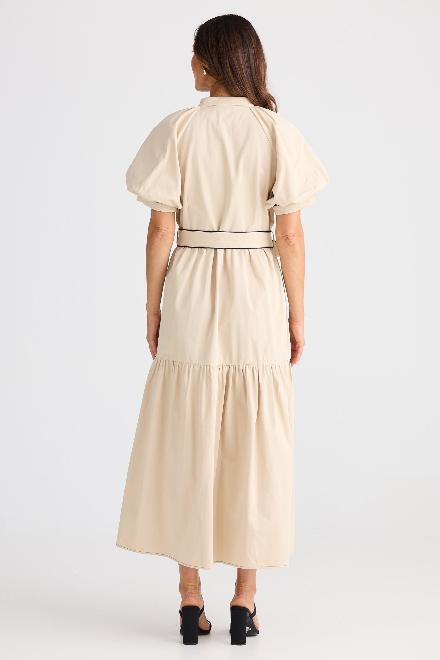 Woman wearing a beige dress with puff sleeves on a white background