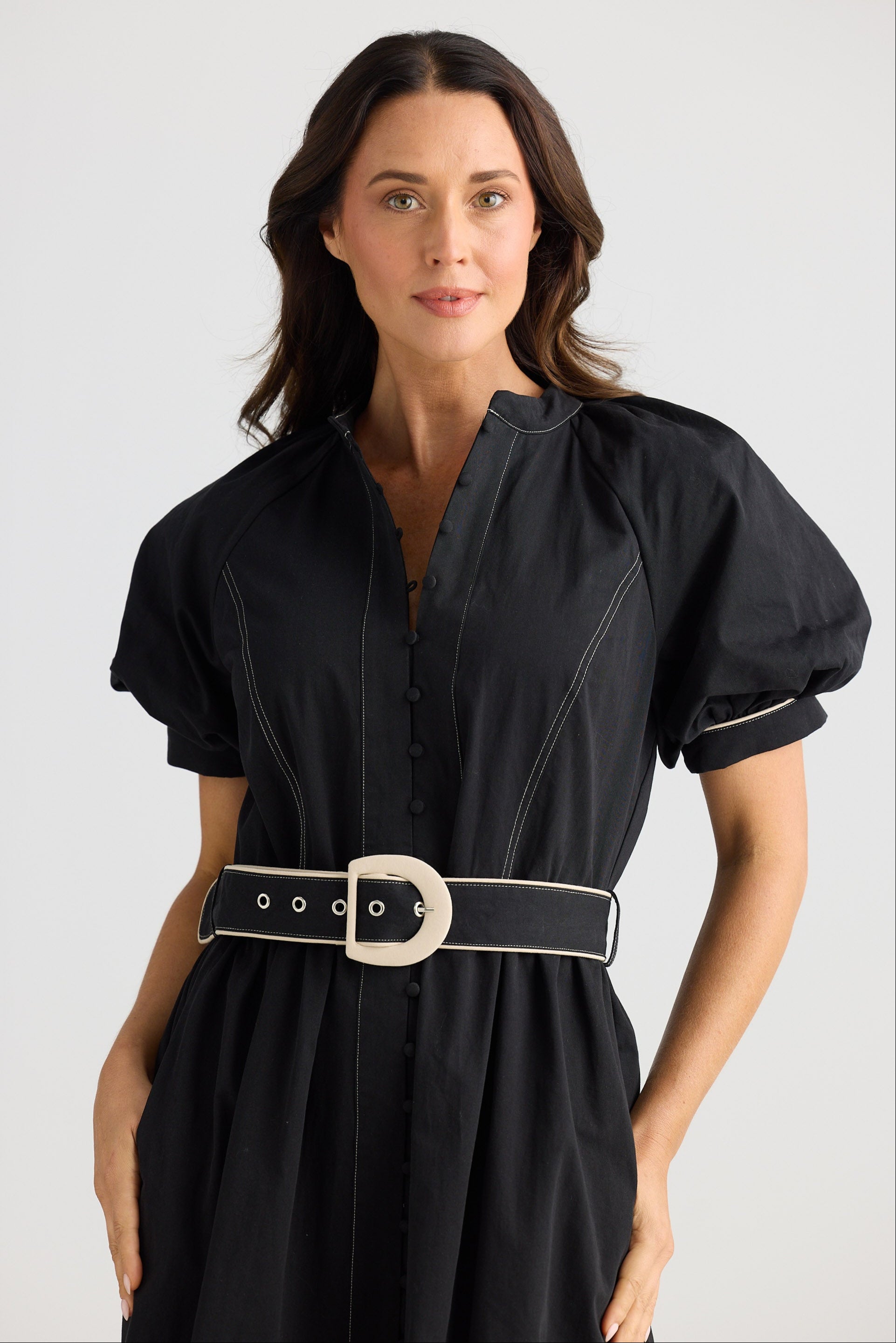 Woman wearing a black dress with a belt on a white background