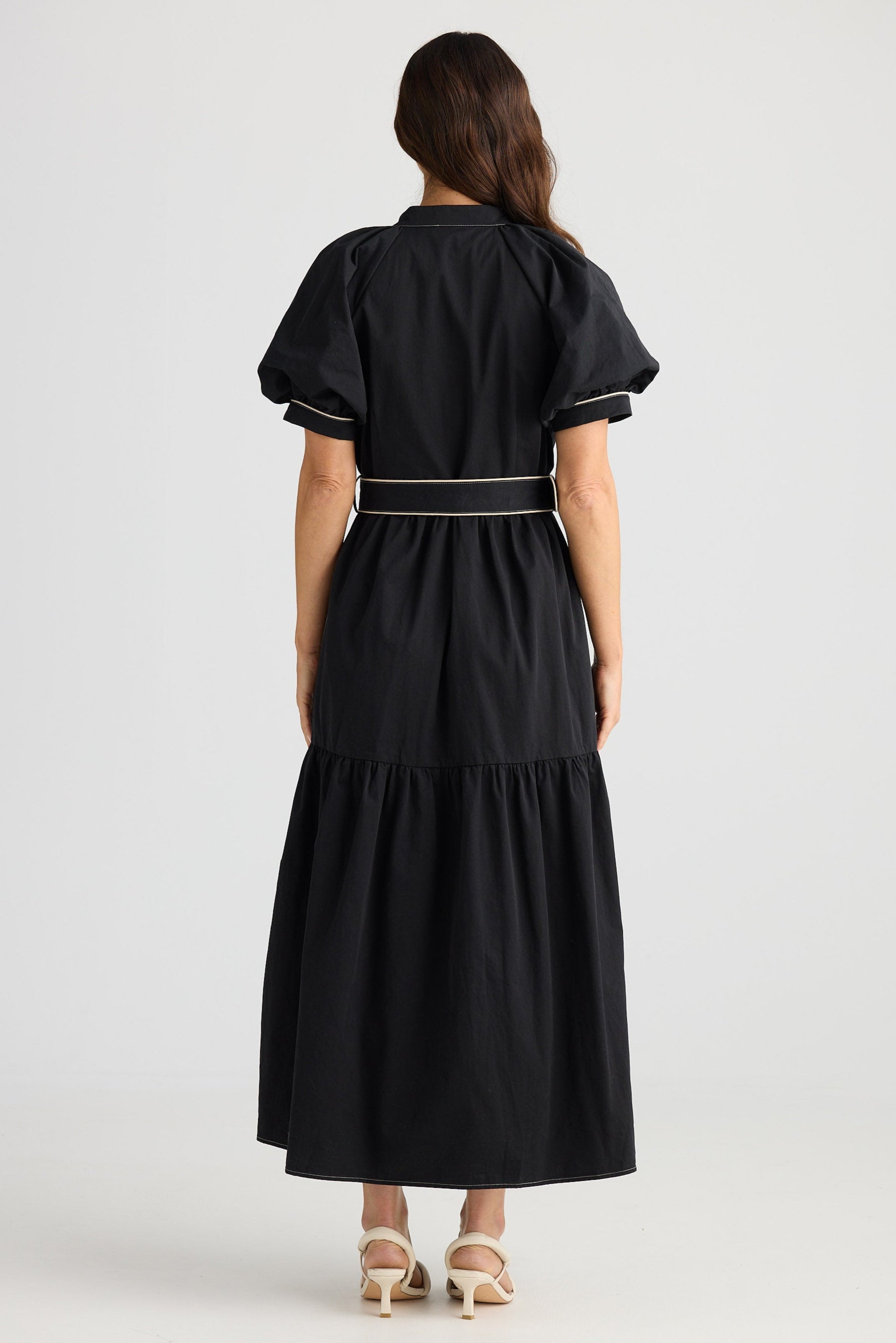 Woman wearing a black dress with a belt on a white background
