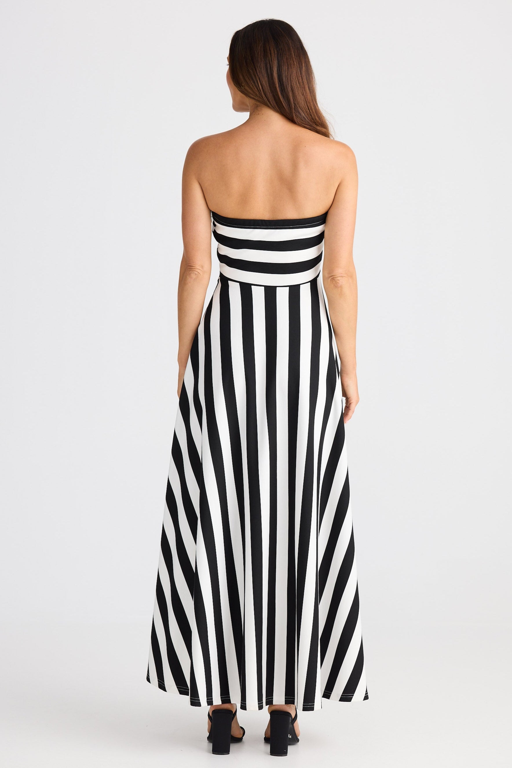 Woman wearing a black and white striped strapless dress on a white background