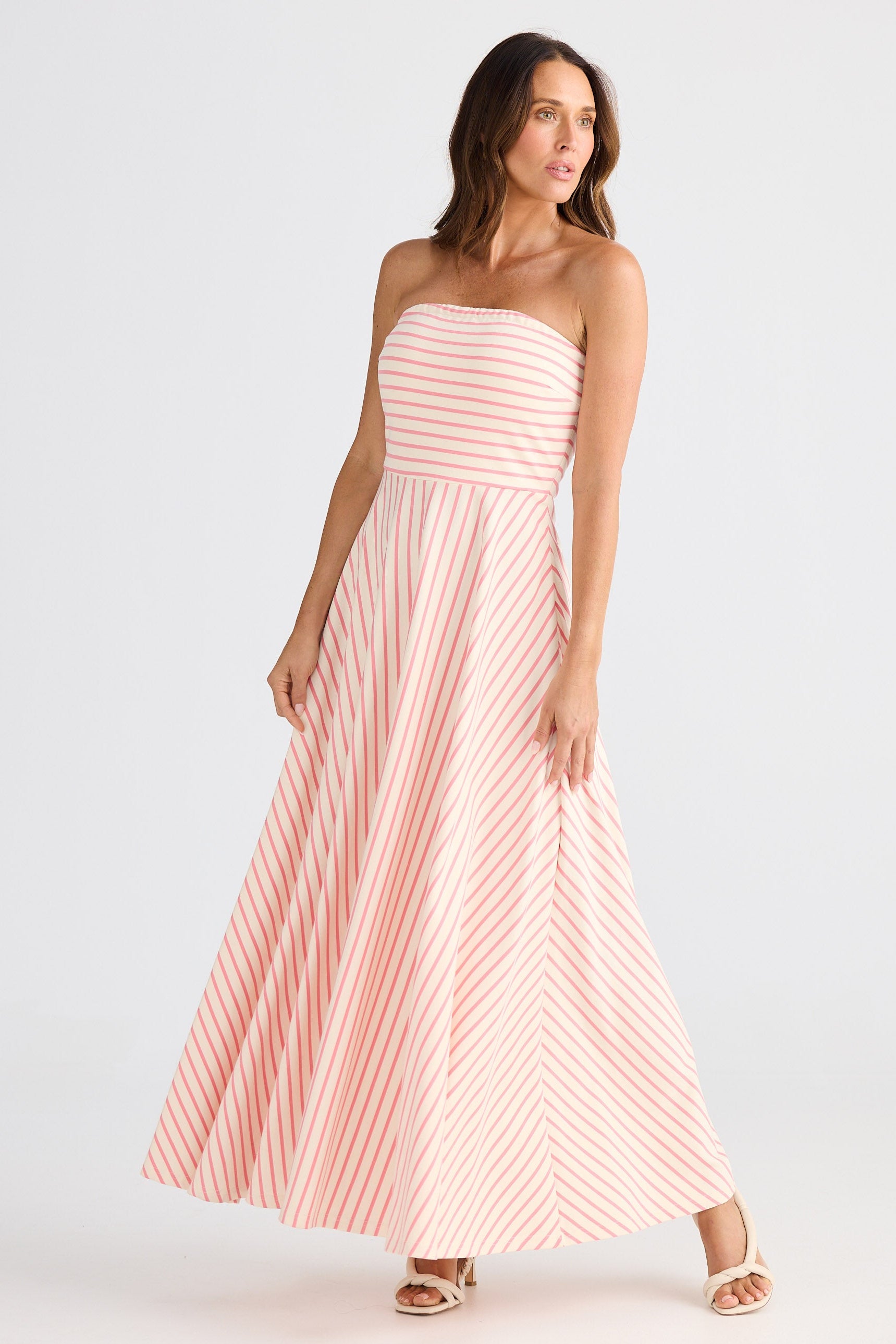 Woman wearing a pink striped strapless dress on a white background