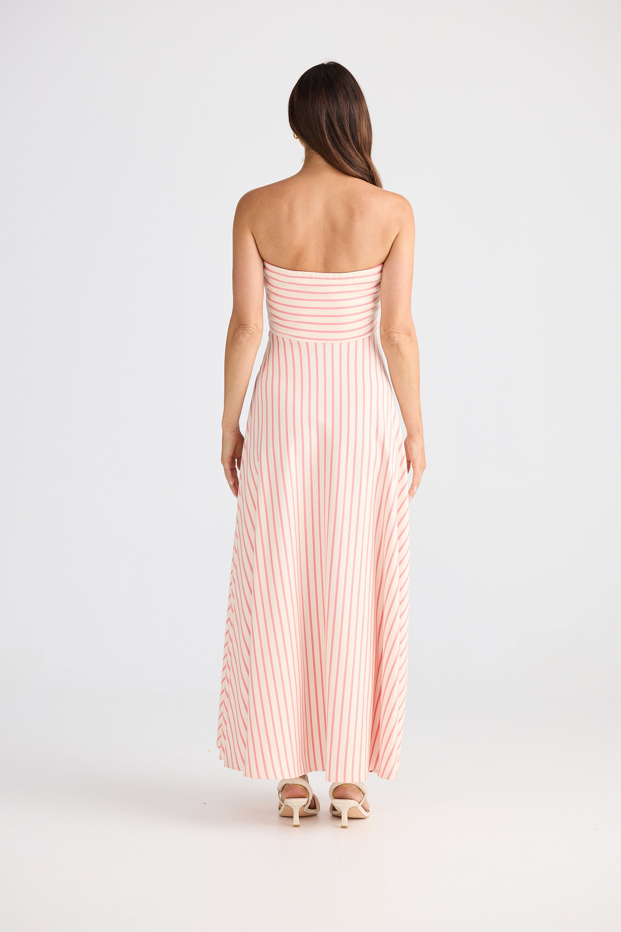Woman wearing a strapless pink and white striped dress on a white background