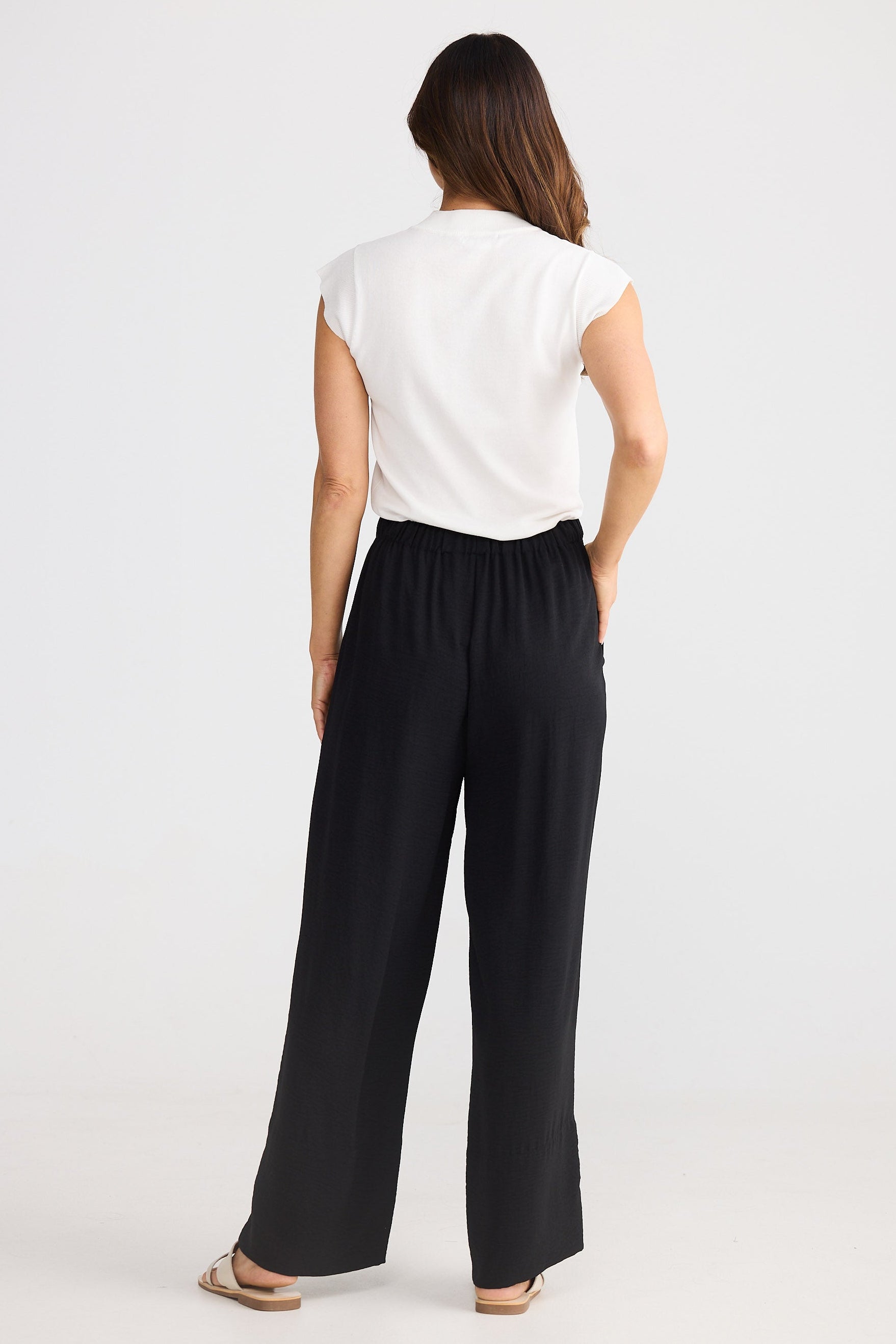 Woman wearing a white top and black wide-leg pants on a white background