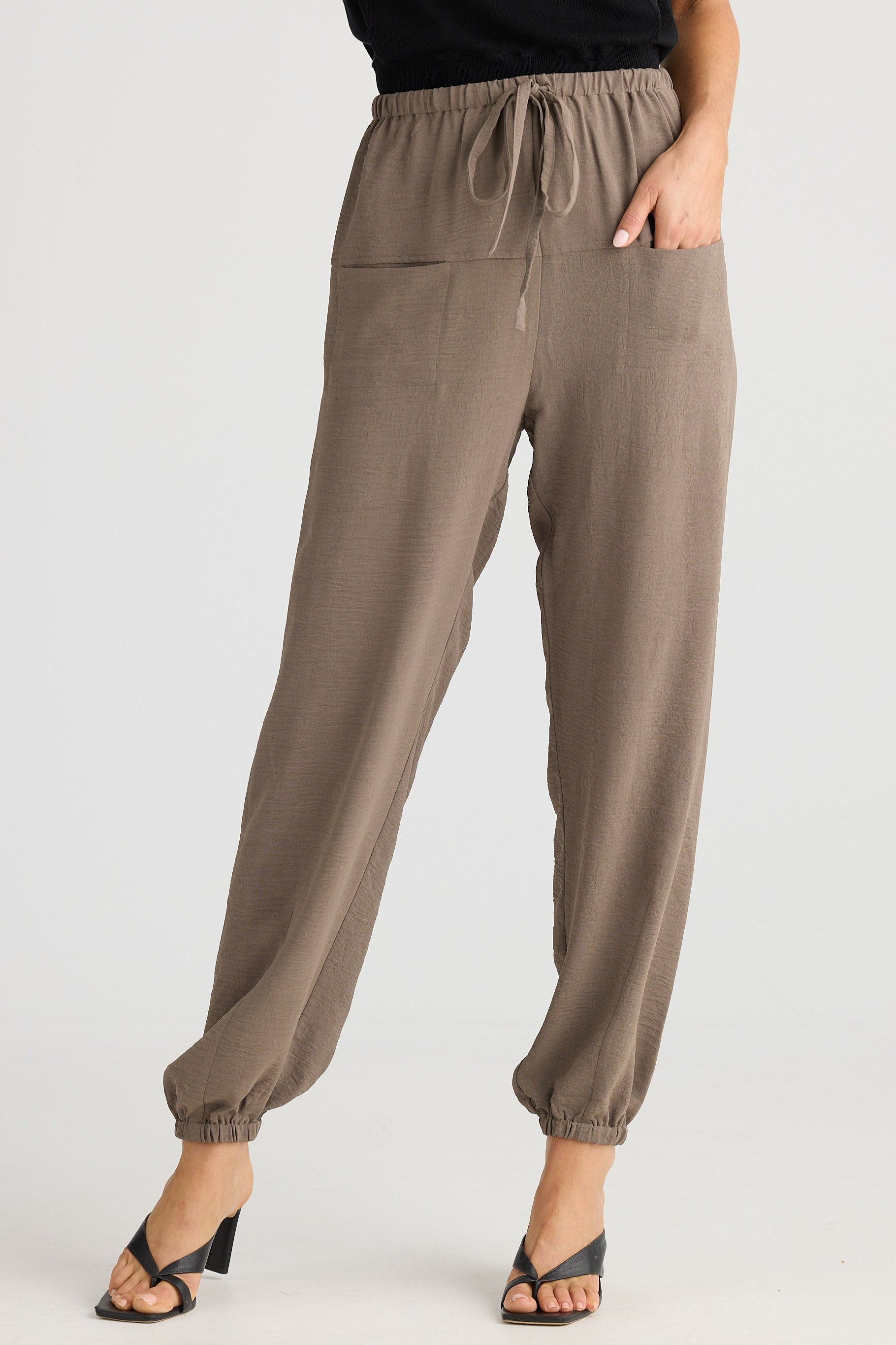 Brown pants worn by a person on a white background