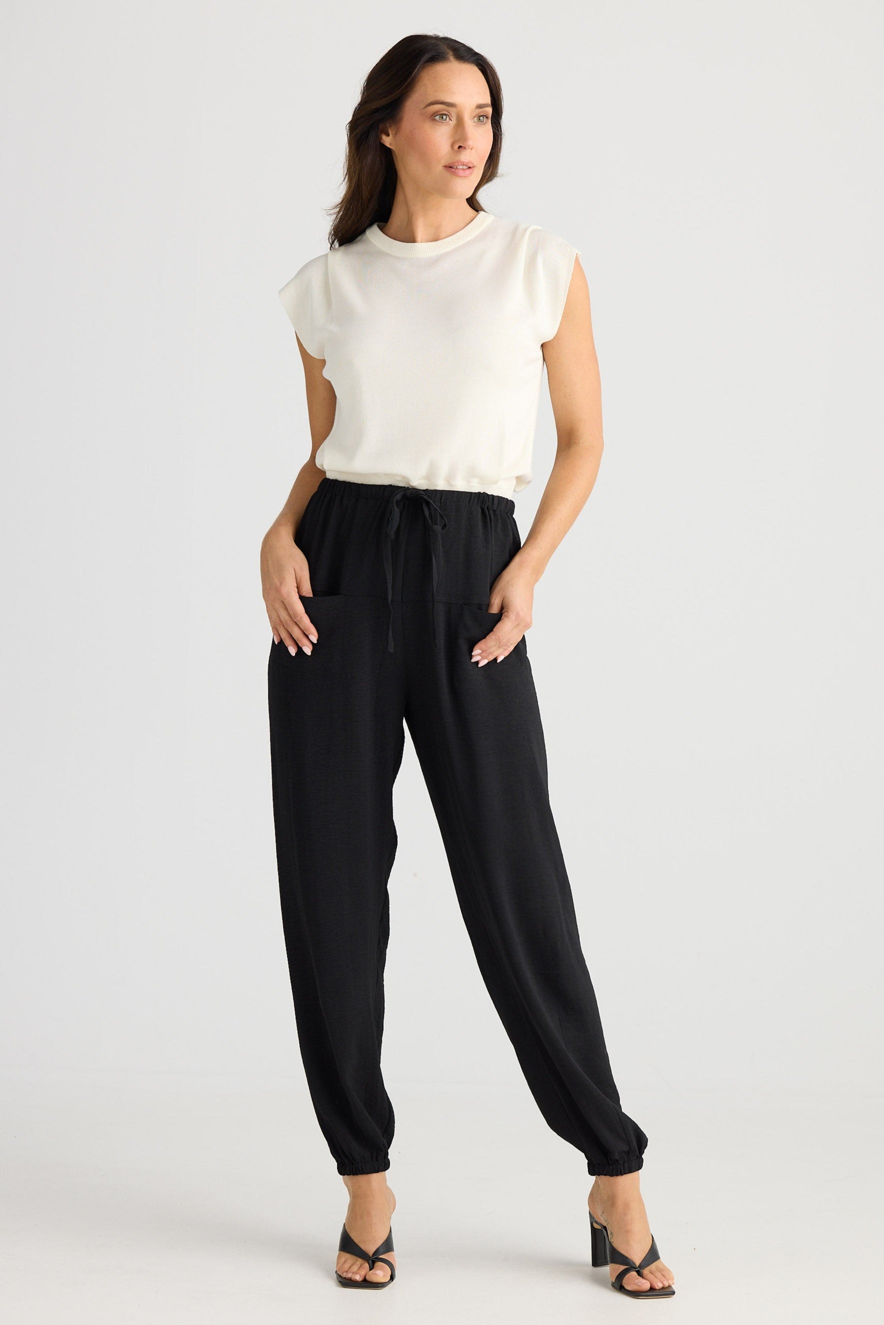 Woman wearing a white blouse and black pants on a white background