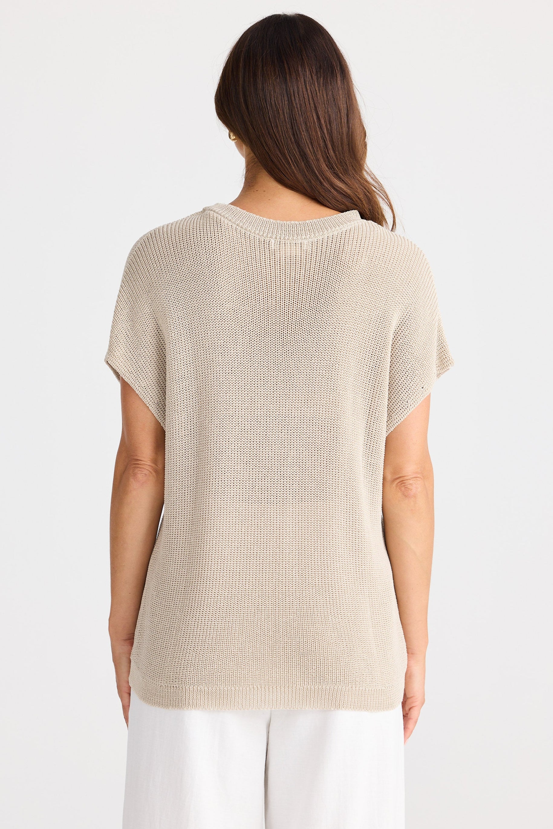 Woman wearing a beige knit sleeveless top on a white background