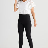 Woman wearing black leggings and a white top on a white background