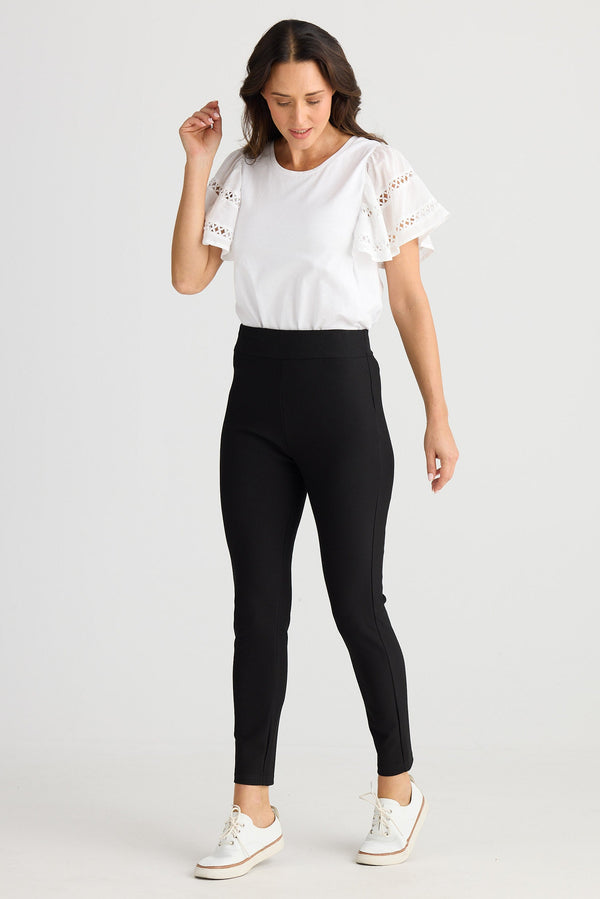Woman wearing black leggings and a white top on a white background