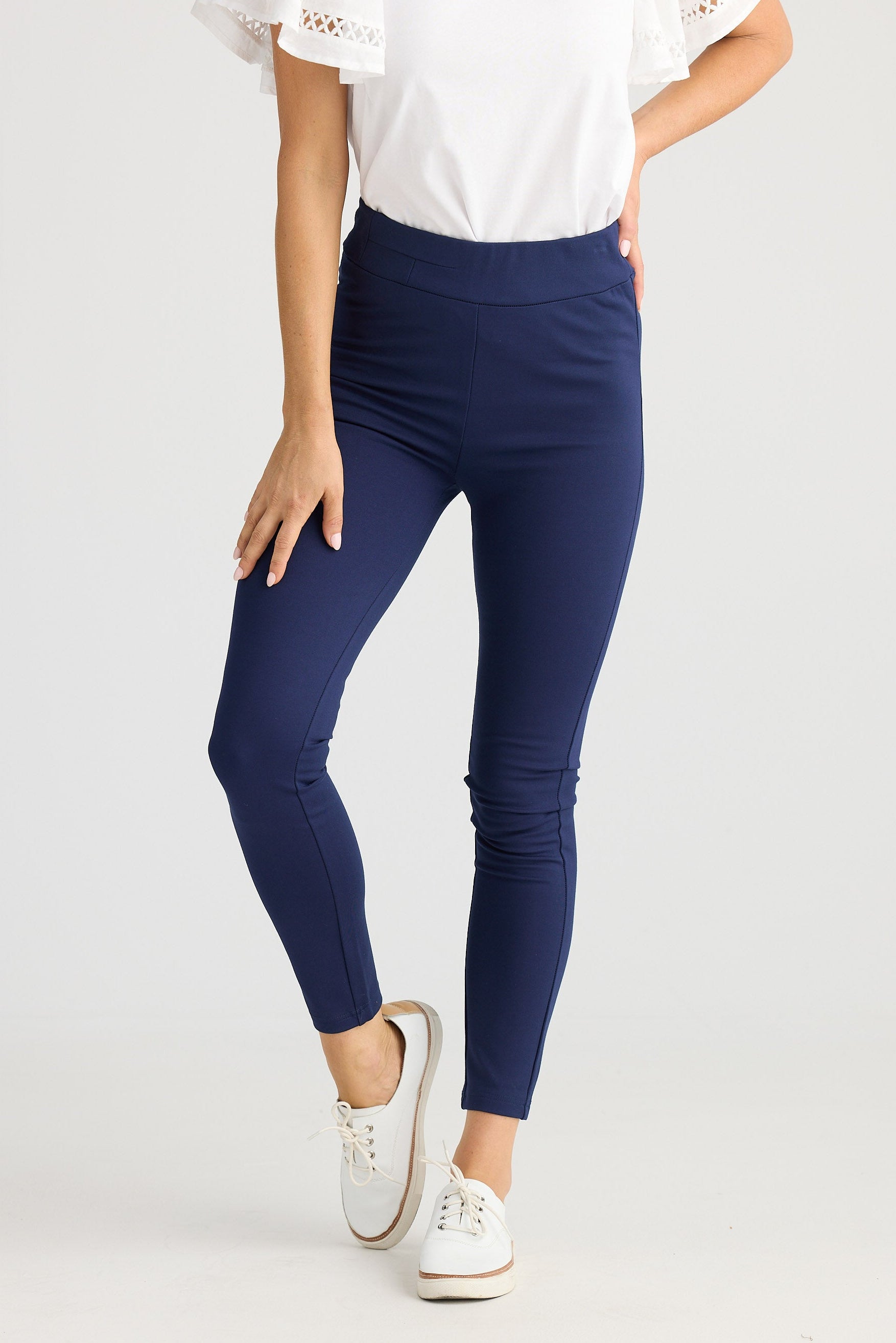 Person wearing navy leggings and white sneakers on a light gray background