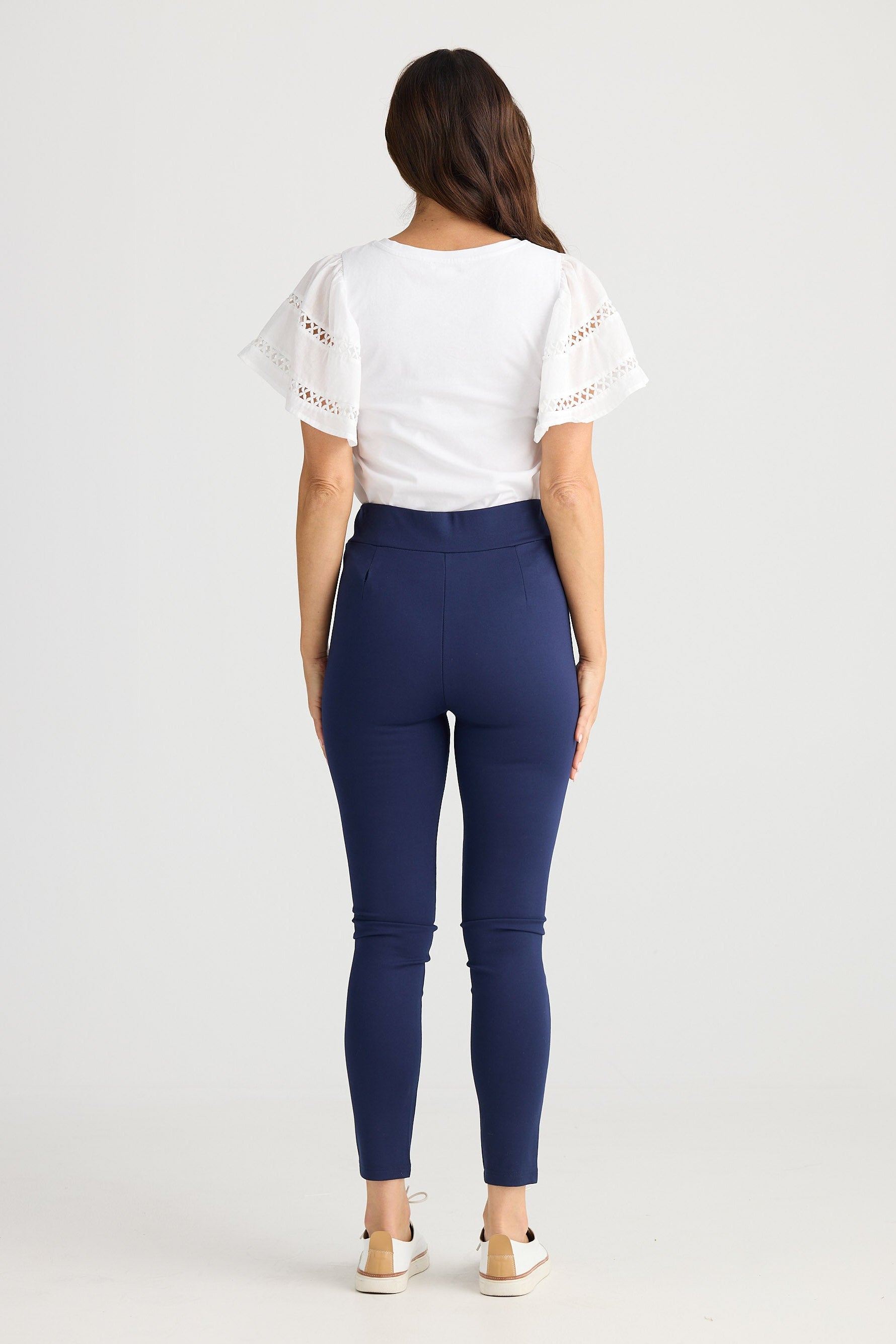 Woman wearing a white top and blue leggings on a white background